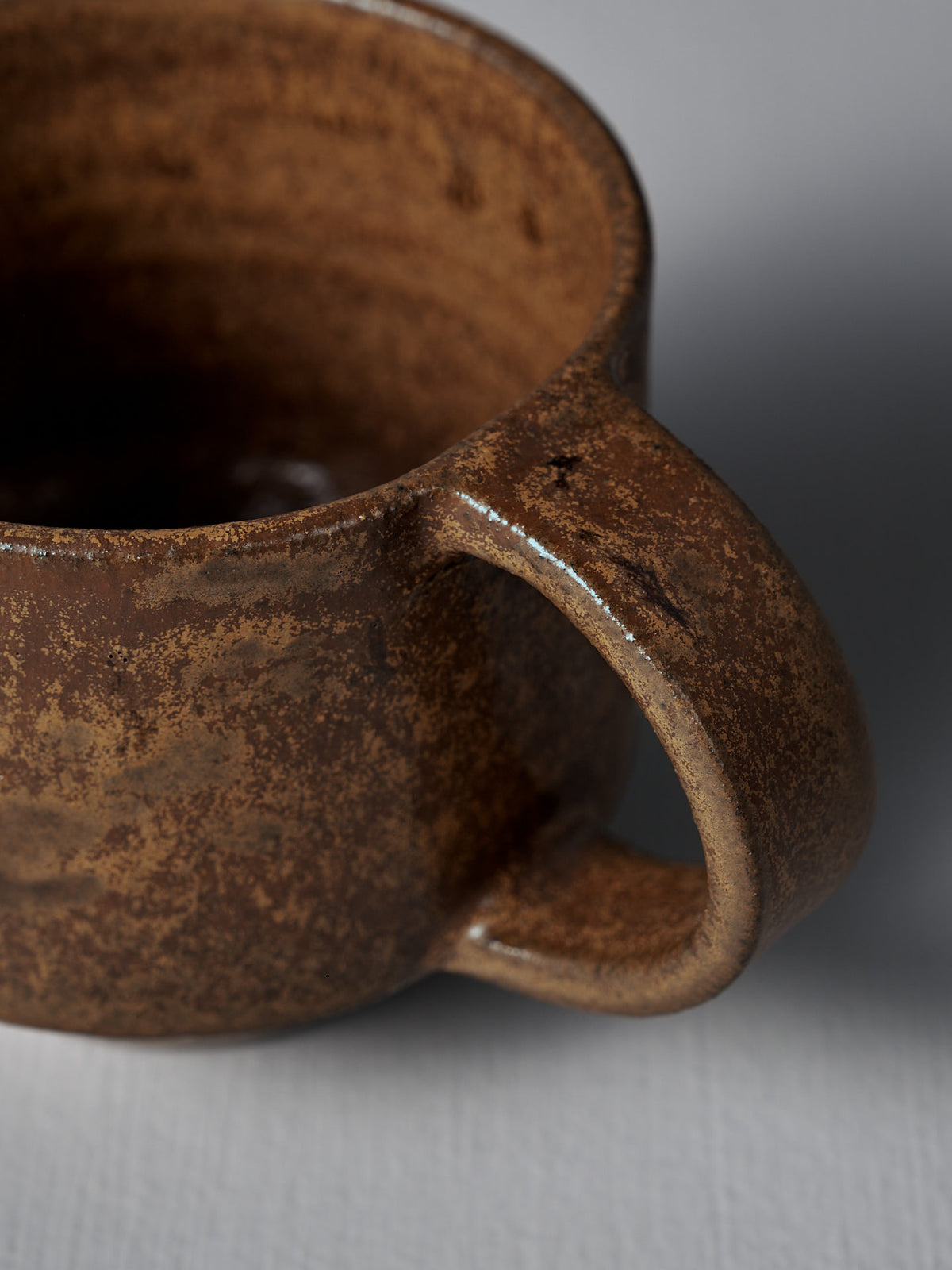 Close-up of the Studio Foon Everyday Stacker Cup – Medium in terracotta, showing its textured, matte finish and handle against a light gray background—a stylish and practical choice for daily use.