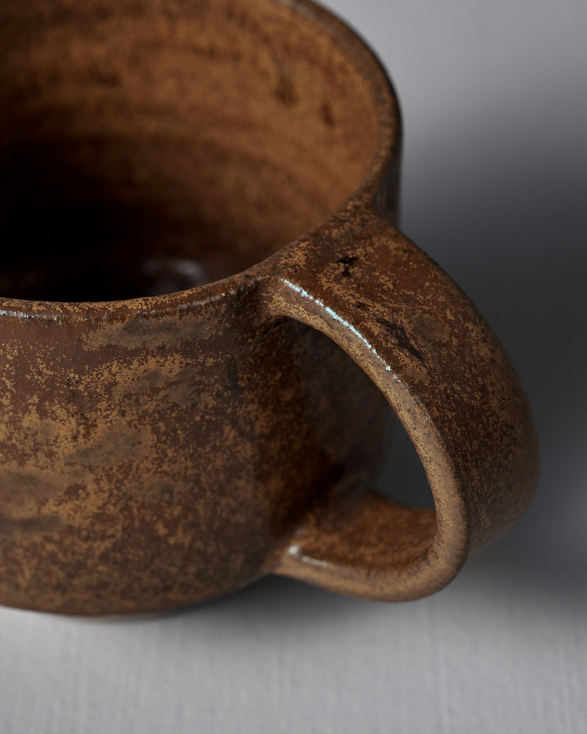 Close-up of the Studio Foon Everyday Stacker Cup – Medium in terracotta, showing its textured, matte finish and handle against a light gray background—a stylish and practical choice for daily use.