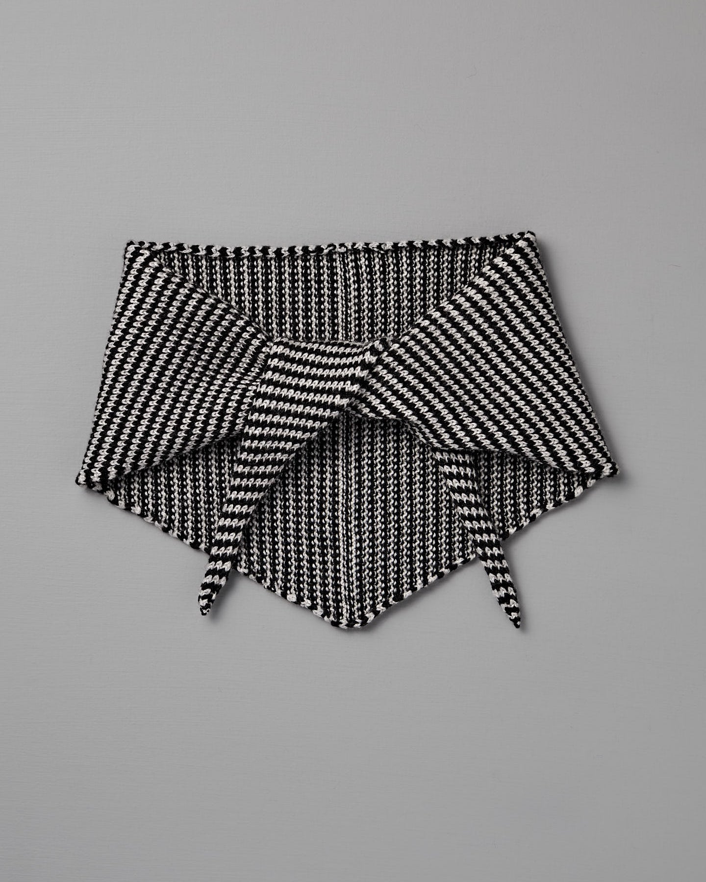 The Daisy Scarf – Black & Creme Stripe features a geometric knit pattern in black and creme, shown flat on a gray background with pointed ends overlapping. Dimensions: 97cm long x 22cm wide.