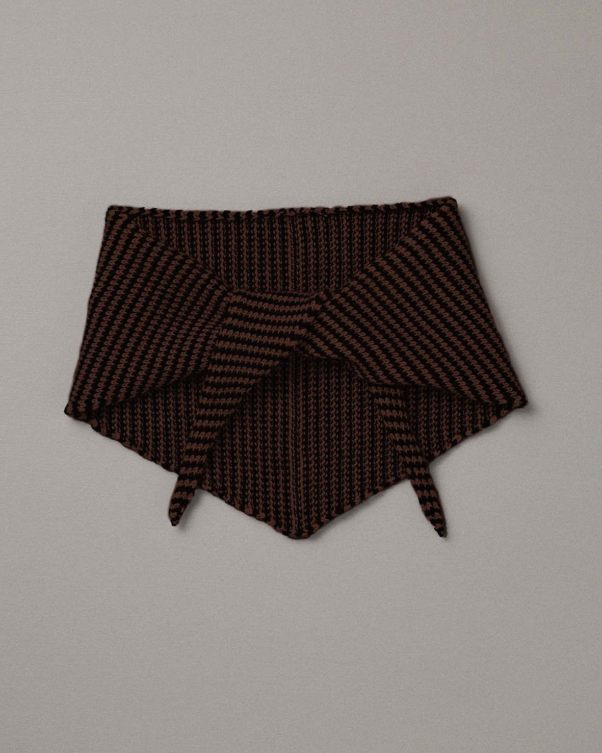 The Daisy Scarf – Chestnut & Black Stripe, a knitted triangular neck warmer, is laid flat on a plain light gray background, its long length reminiscent of a yoga mat.