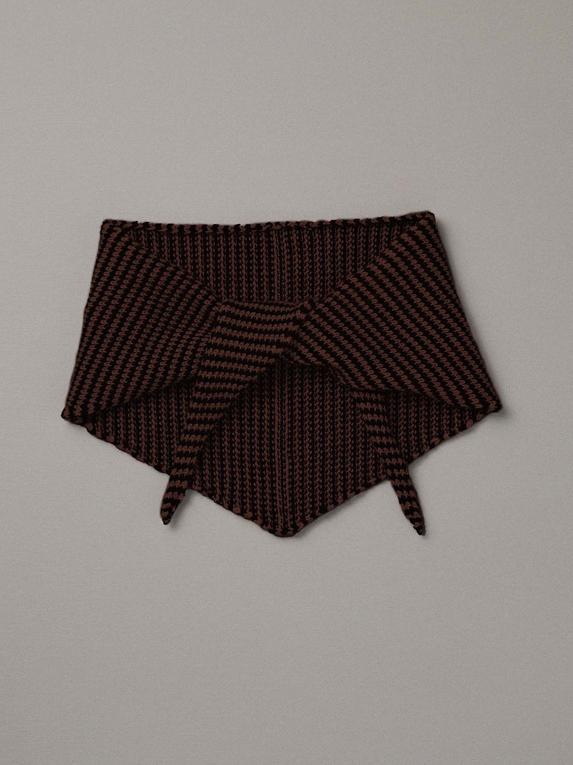 The Daisy Scarf – Chestnut & Black Stripe, a knitted triangular neck warmer, is laid flat on a plain light gray background, its long length reminiscent of a yoga mat.