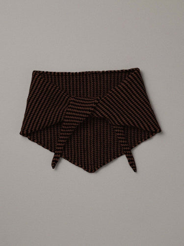 The Daisy Scarf – Chestnut & Black Stripe, a knitted triangular neck warmer, is laid flat on a plain light gray background, its long length reminiscent of a yoga mat.