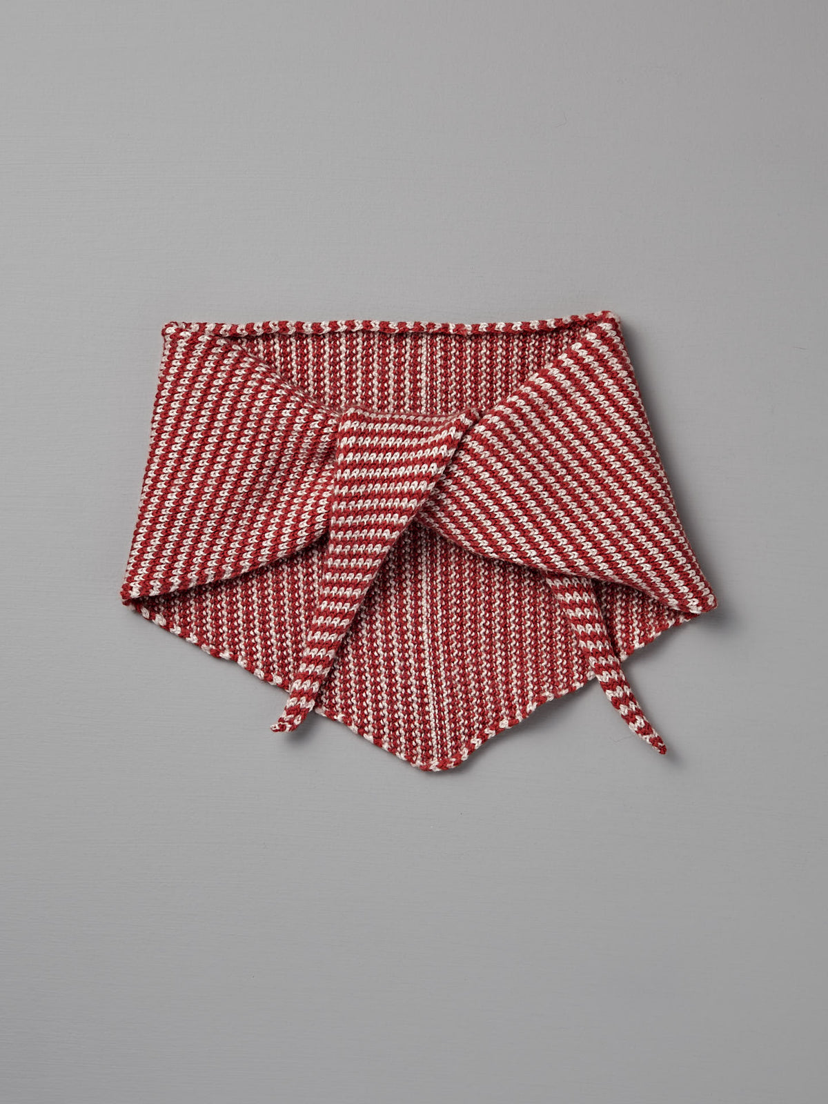 The Francie Daisy Scarf – Cherry Stripe features red and white stripes with pointed ends and folded sections, shown flat on a gray background. Size: 22cm wide by 97cm long.