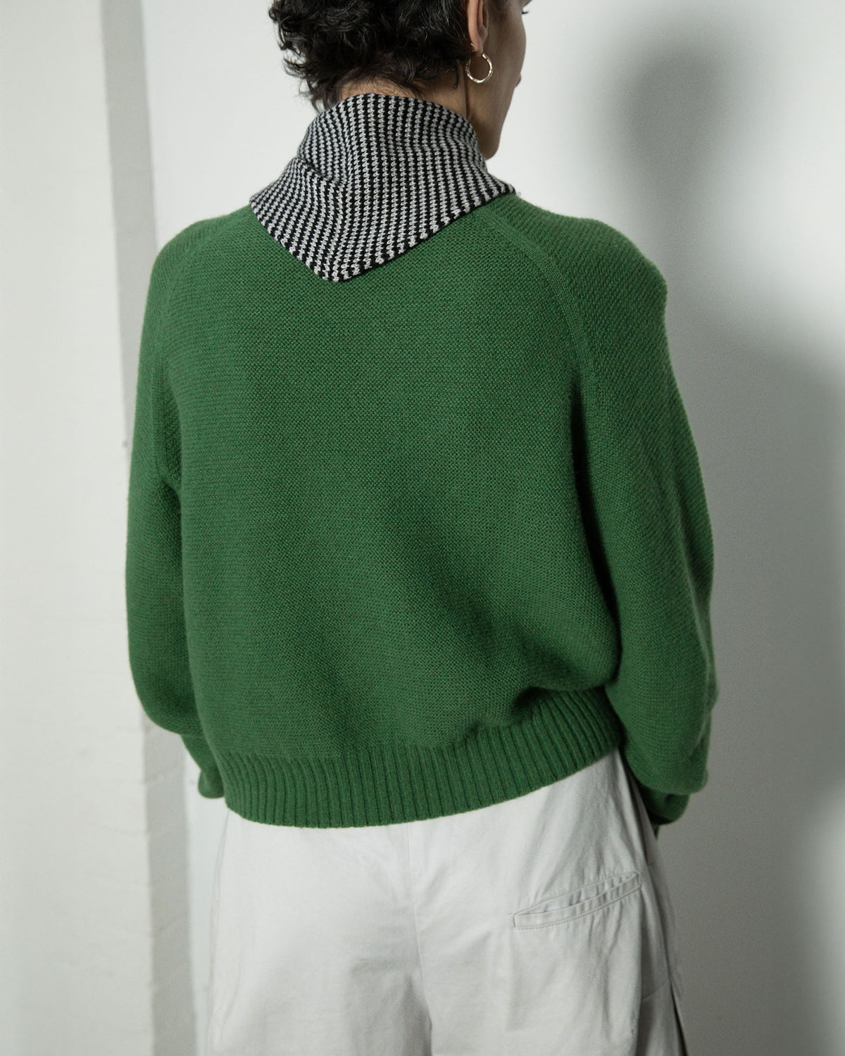 Person standing with their back to the camera, wearing white pants and a green sweater paired with the Daisy Scarf – Black & Creme Stripe. The scarf is 97cm long and 22cm wide.