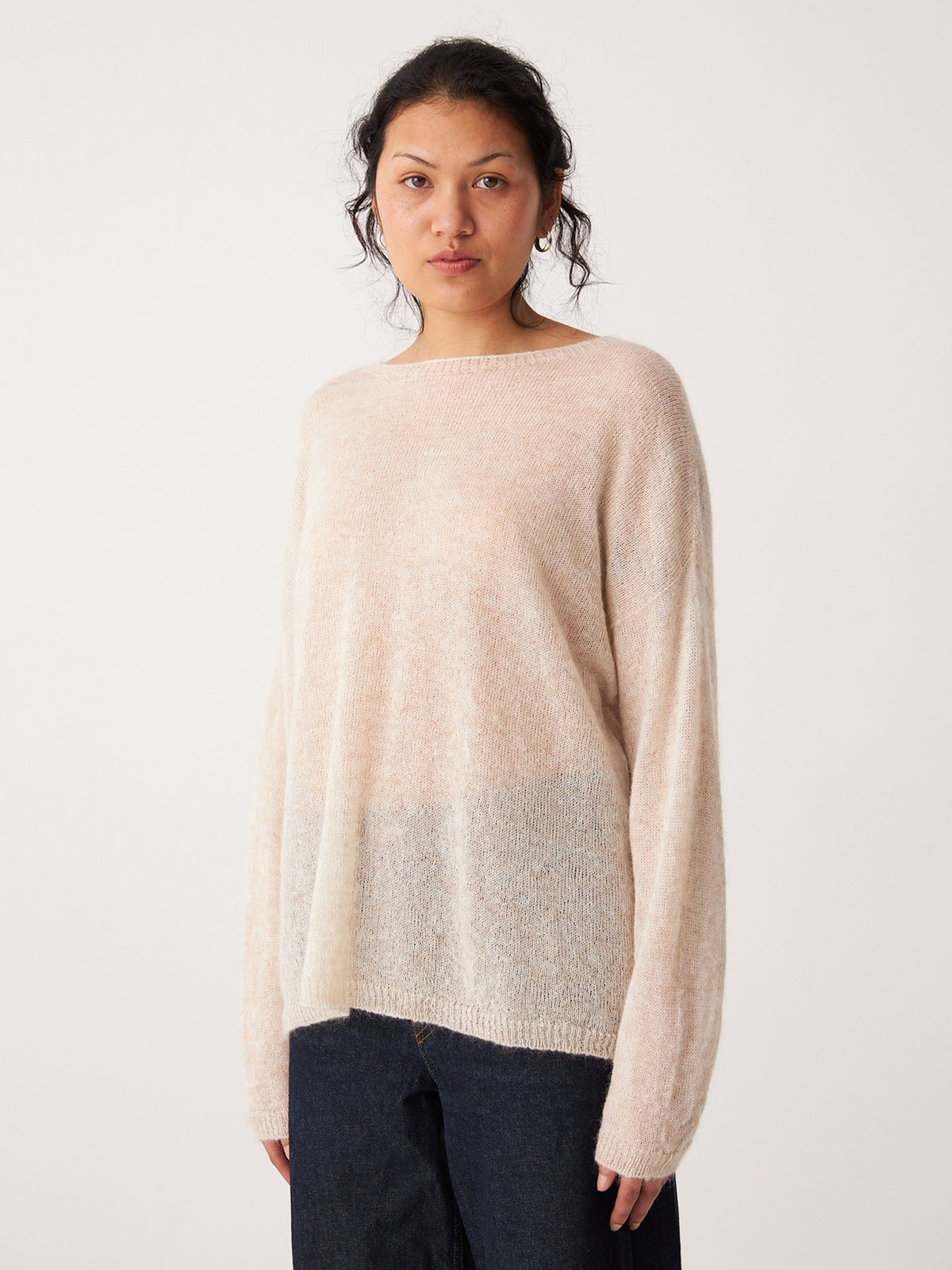 Person wearing a relaxed fit, long-sleeve Feather Knit – Creme sweater with dark pants, standing against a plain white background.