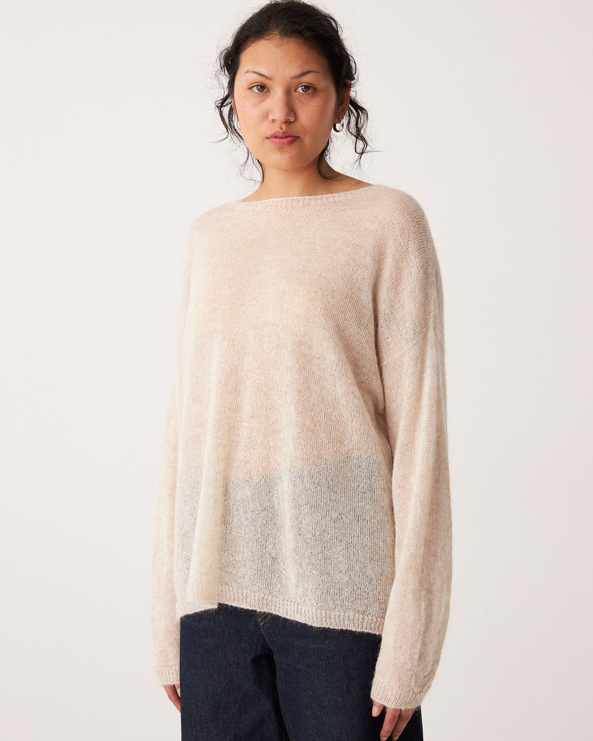 Person wearing a relaxed fit, long-sleeve Feather Knit – Creme sweater with dark pants, standing against a plain white background.