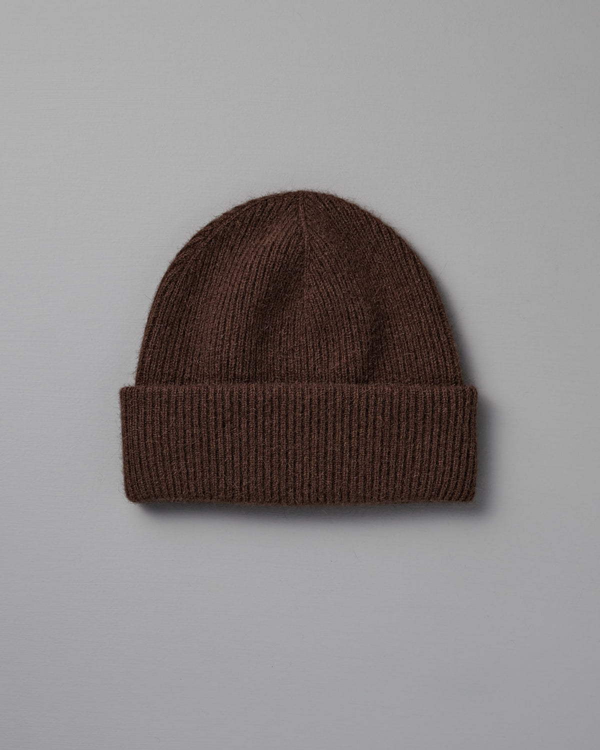 The Hinoki Beanie – Chestnut, a brown knitted hat with a folded brim, is shown on a plain light gray background.