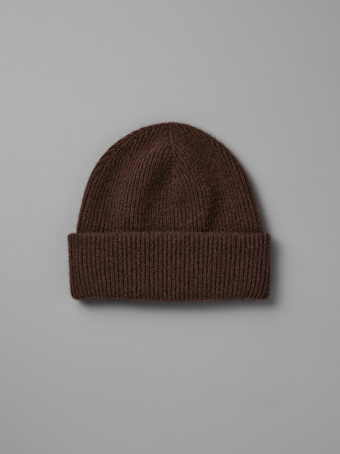 The Hinoki Beanie – Chestnut, a brown knitted hat with a folded brim, is shown on a plain light gray background.