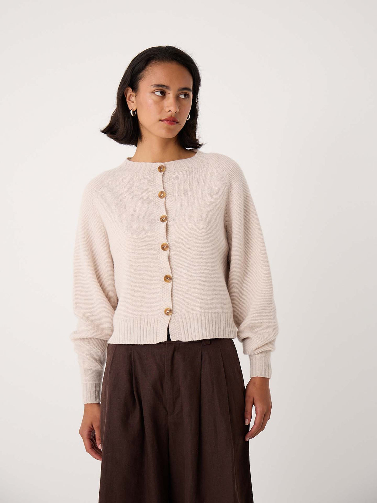 A woman wearing a Loft Cardigan – Creme and a dark brown skirt stands against a plain white background.