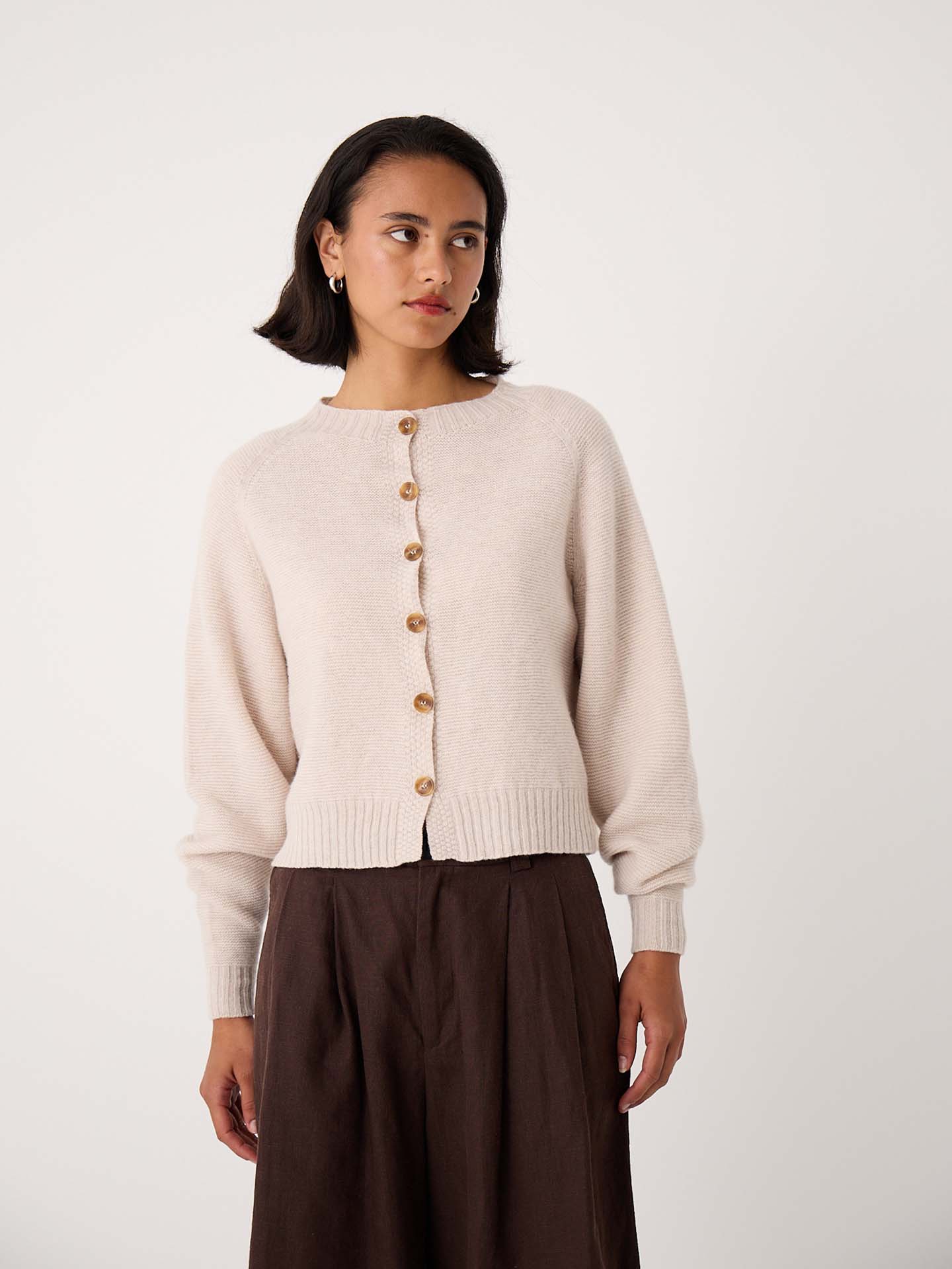 A woman wearing a Loft Cardigan – Creme and a dark brown skirt stands against a plain white background.