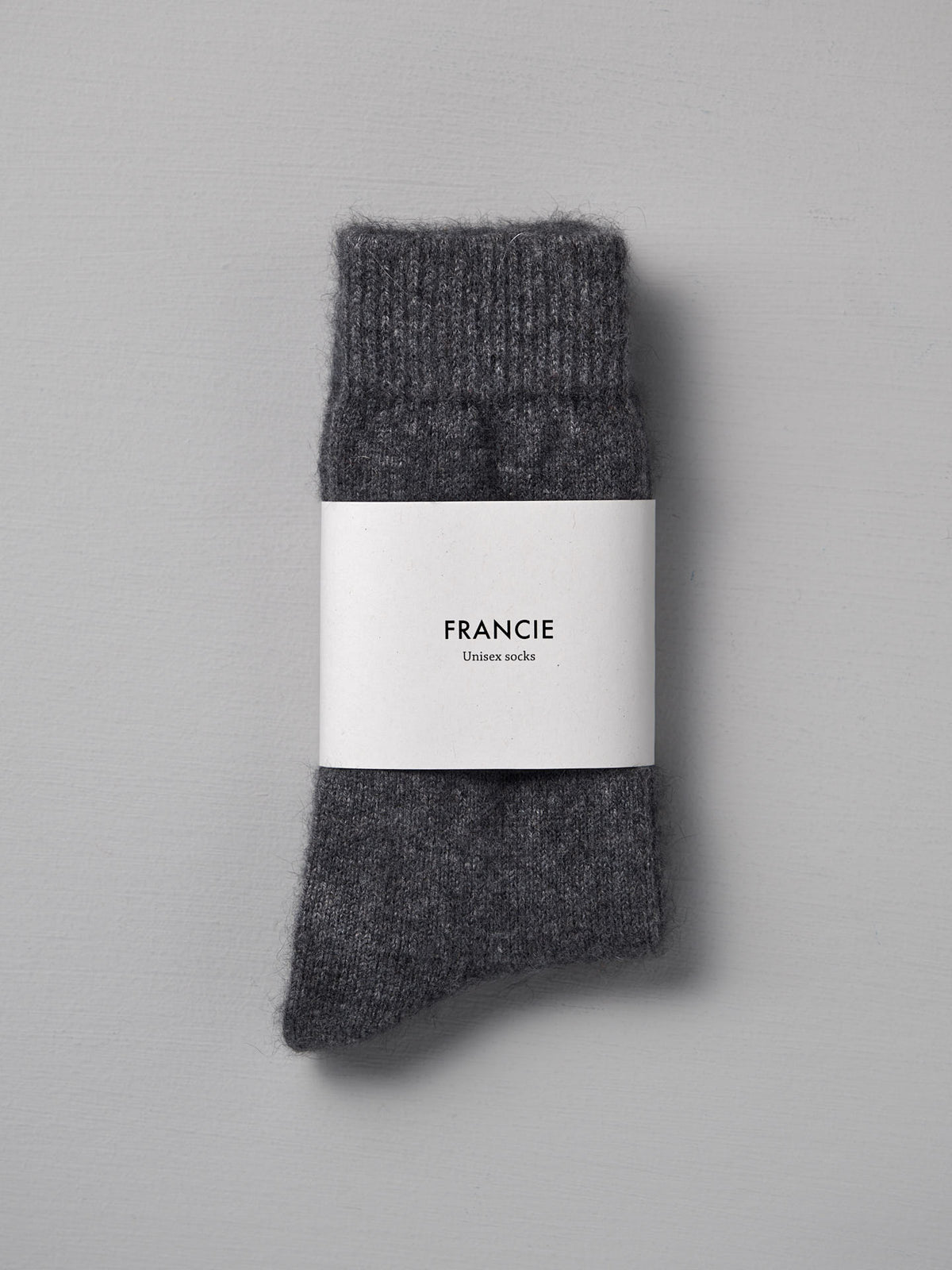 A pair of folded Possum Merino Socks – Charcoal by Francie is displayed on a light gray background, available in small, medium, and large to fit standard UK, US, and EUR shoe sizes.