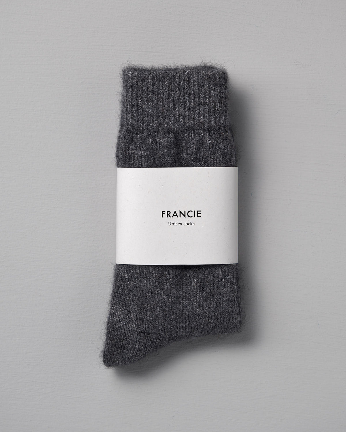 A pair of folded Possum Merino Socks – Charcoal by Francie is displayed on a light gray background, available in small, medium, and large to fit standard UK, US, and EUR shoe sizes.