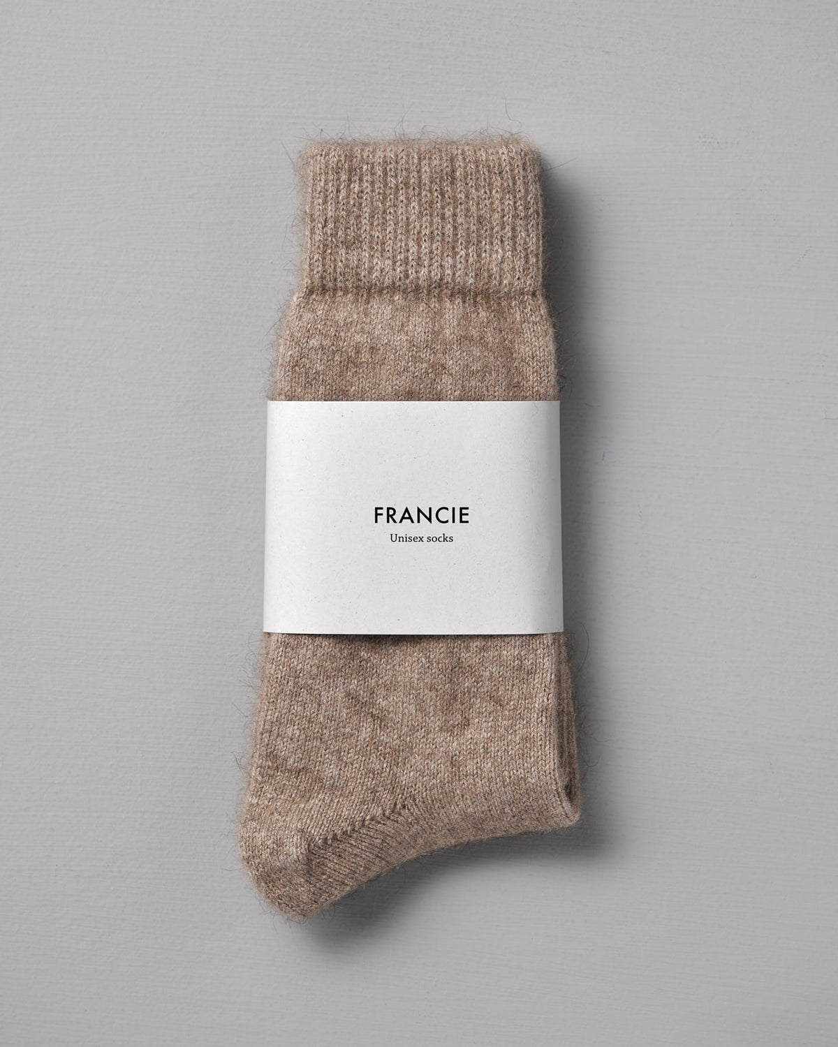 A pair of beige Francie Possum Merino Socks – Natural, neatly folded with a white "Francie" label on a plain grey background. Available in small, medium, and large with an easy-to-read size chart for EUR, UK, and US shoe sizes.