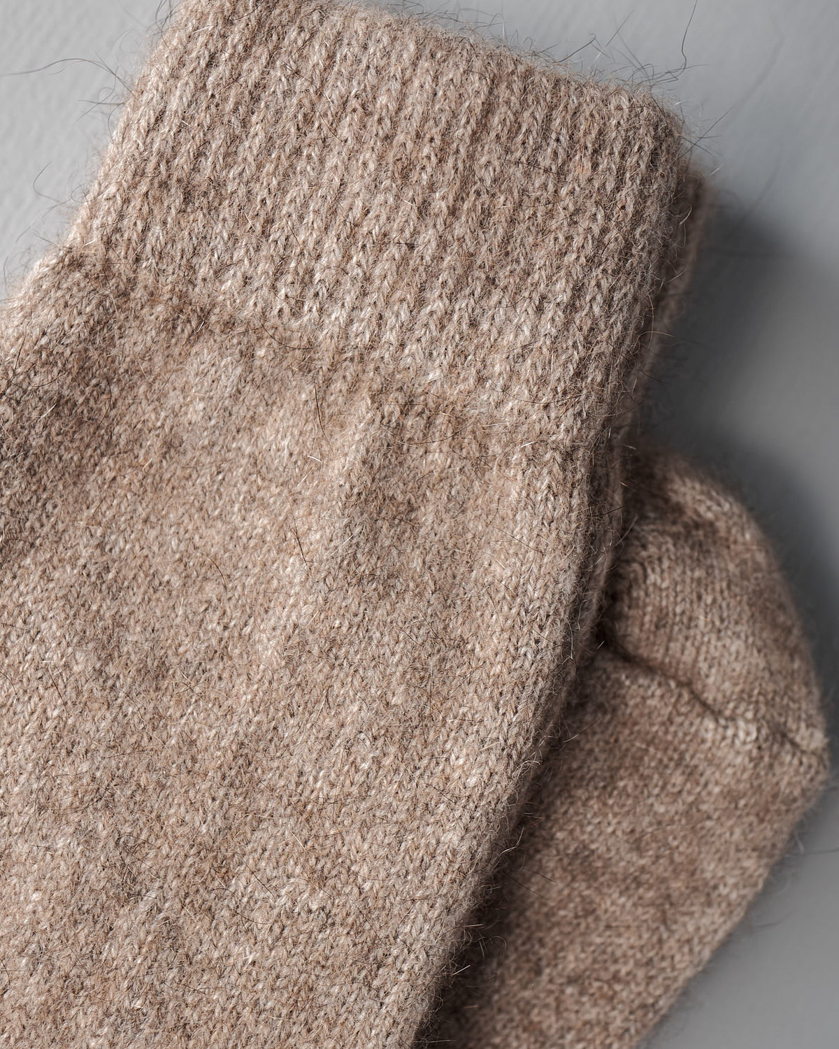 A close-up of two Francie Possum Merino Socks – Natural with ribbed cuffs on a gray surface, available in small, medium, and large sizes with an easy shoe size chart for EUR, UK, and US.