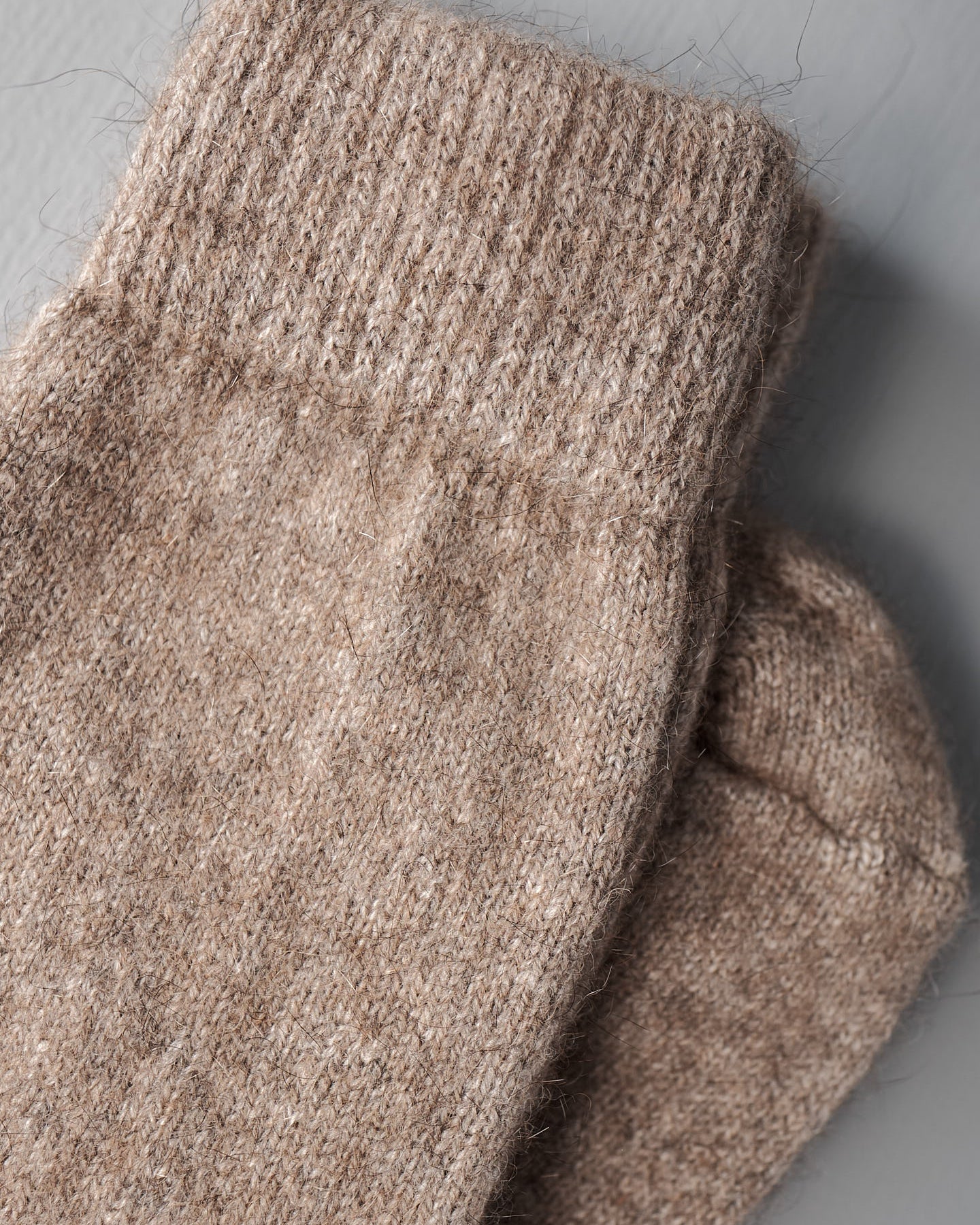A pair of Possum Merino Socks – Natural from Francie laid flat on a gray surface.