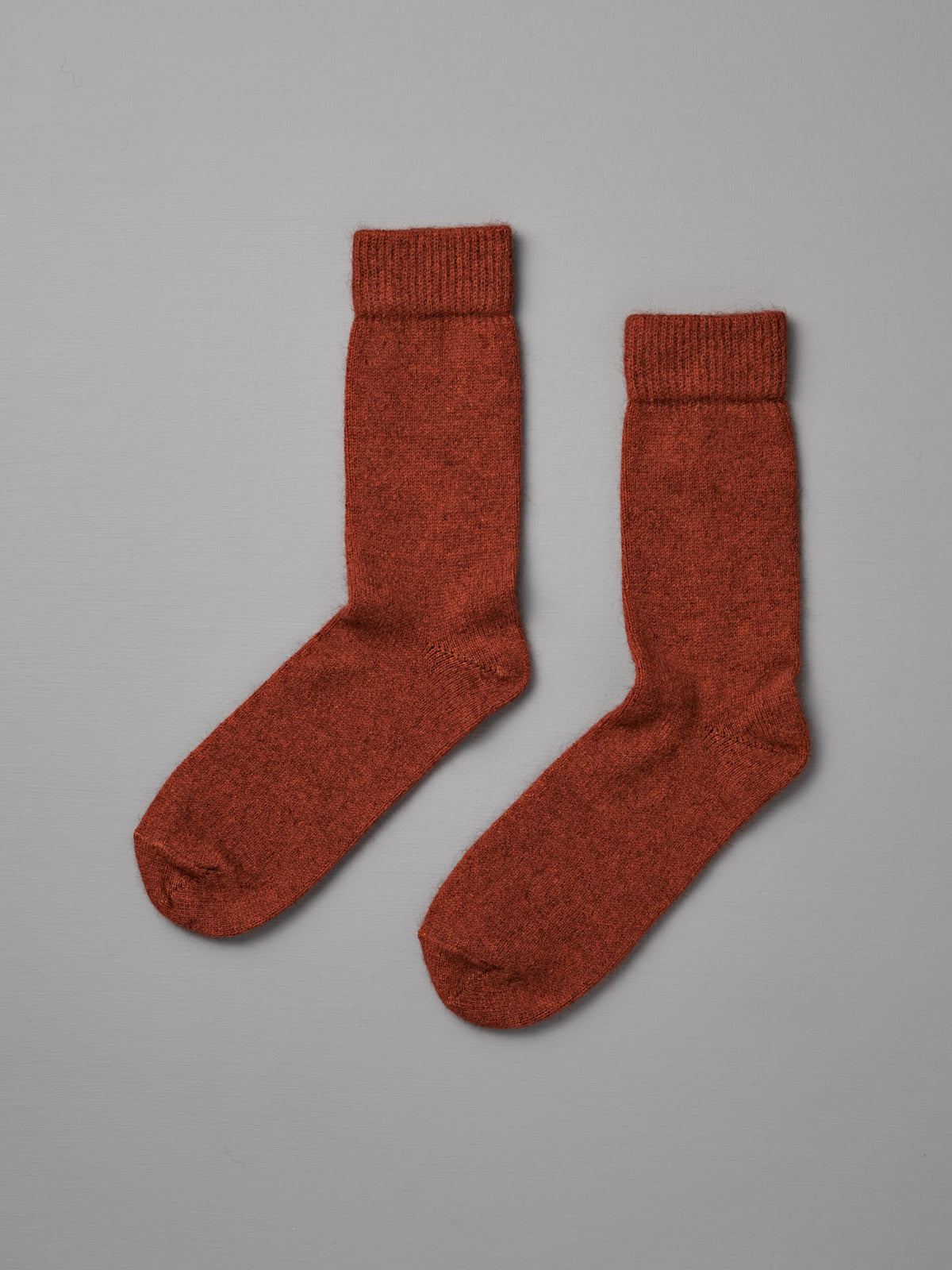 Possum Merino Socks – Amber, shown flat on a light gray background, are rust-colored wool socks available in small, medium, and large with clear UK/US/EUR sizing for the perfect fit.