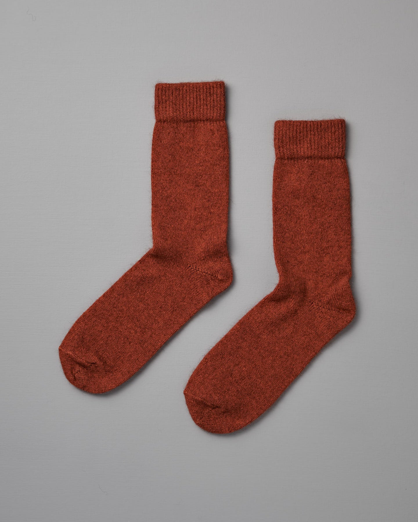 Possum Merino Socks – Amber, shown flat on a light gray background, are rust-colored wool socks available in small, medium, and large with clear UK/US/EUR sizing for the perfect fit.
