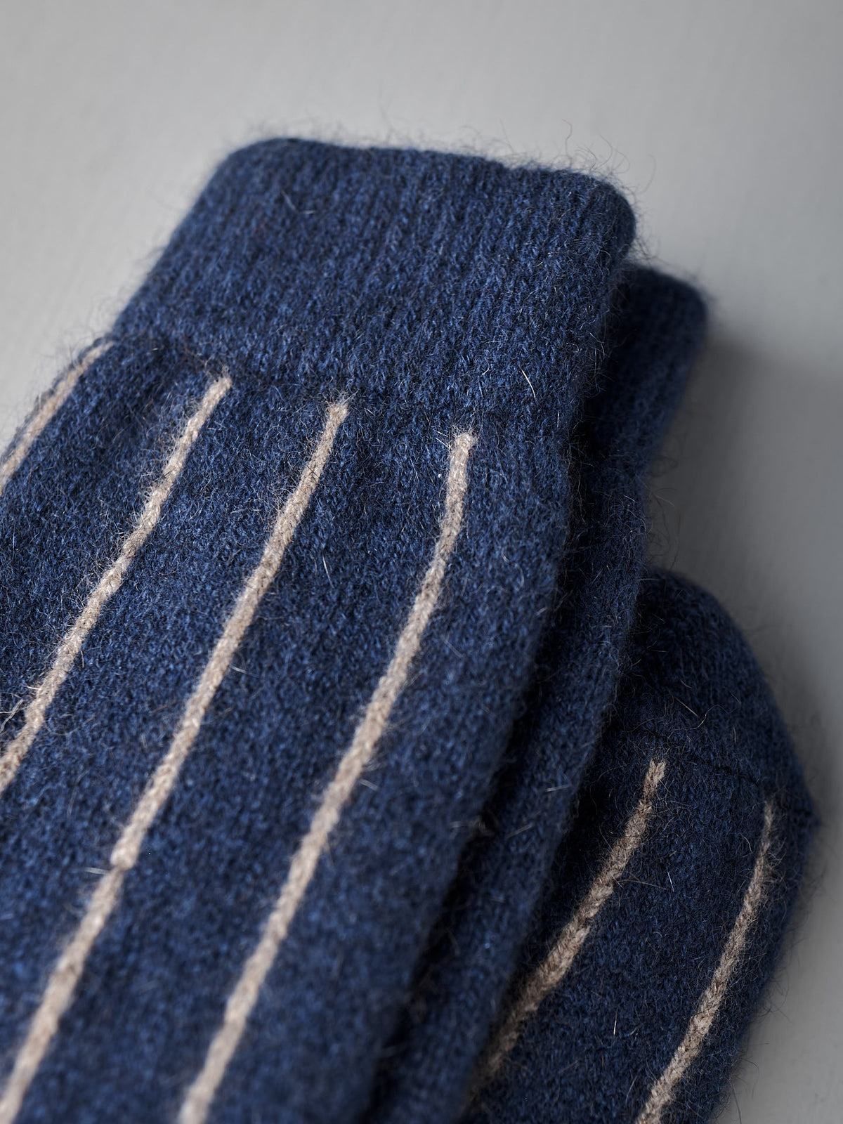 Close-up of Francie&#39;s Possum Merino Socks – Blue &amp; Natural Stripe on a light gray surface, available in small, medium, and large sizes—see our sock size chart for the perfect fit.
