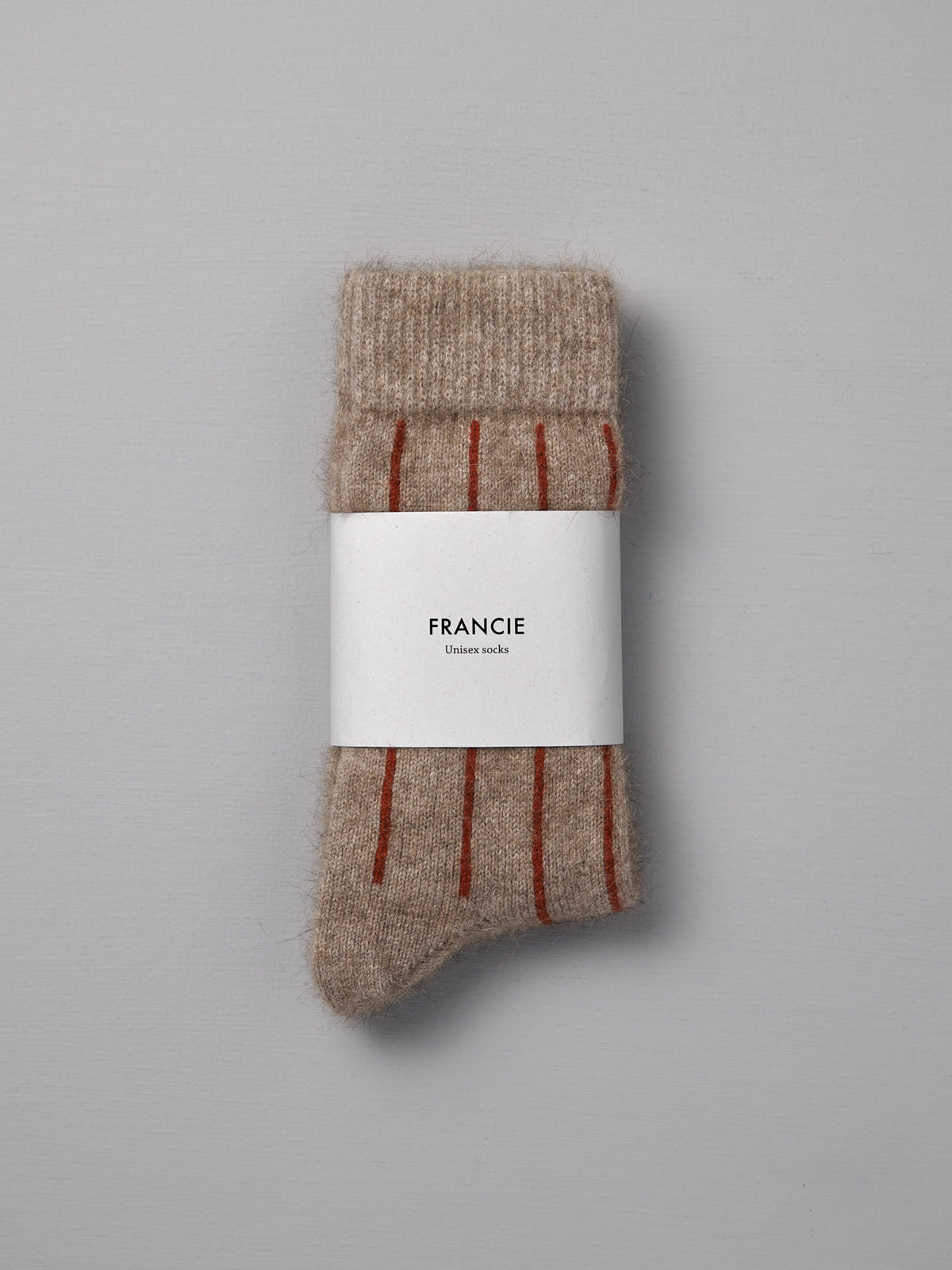 A pair of Francie Possum Merino Socks in Natural &amp; Poppy Stripe, folded with a branded label and shown on a gray background—available in small, medium, and large; easy shoe size chart included.