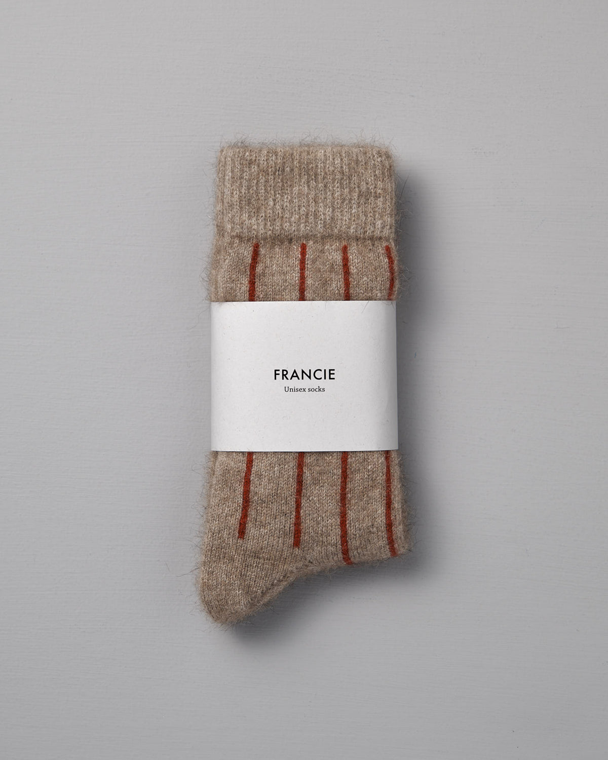 A pair of Francie Possum Merino Socks in Natural & Poppy Stripe, folded with a branded label and shown on a gray background—available in small, medium, and large; easy shoe size chart included.