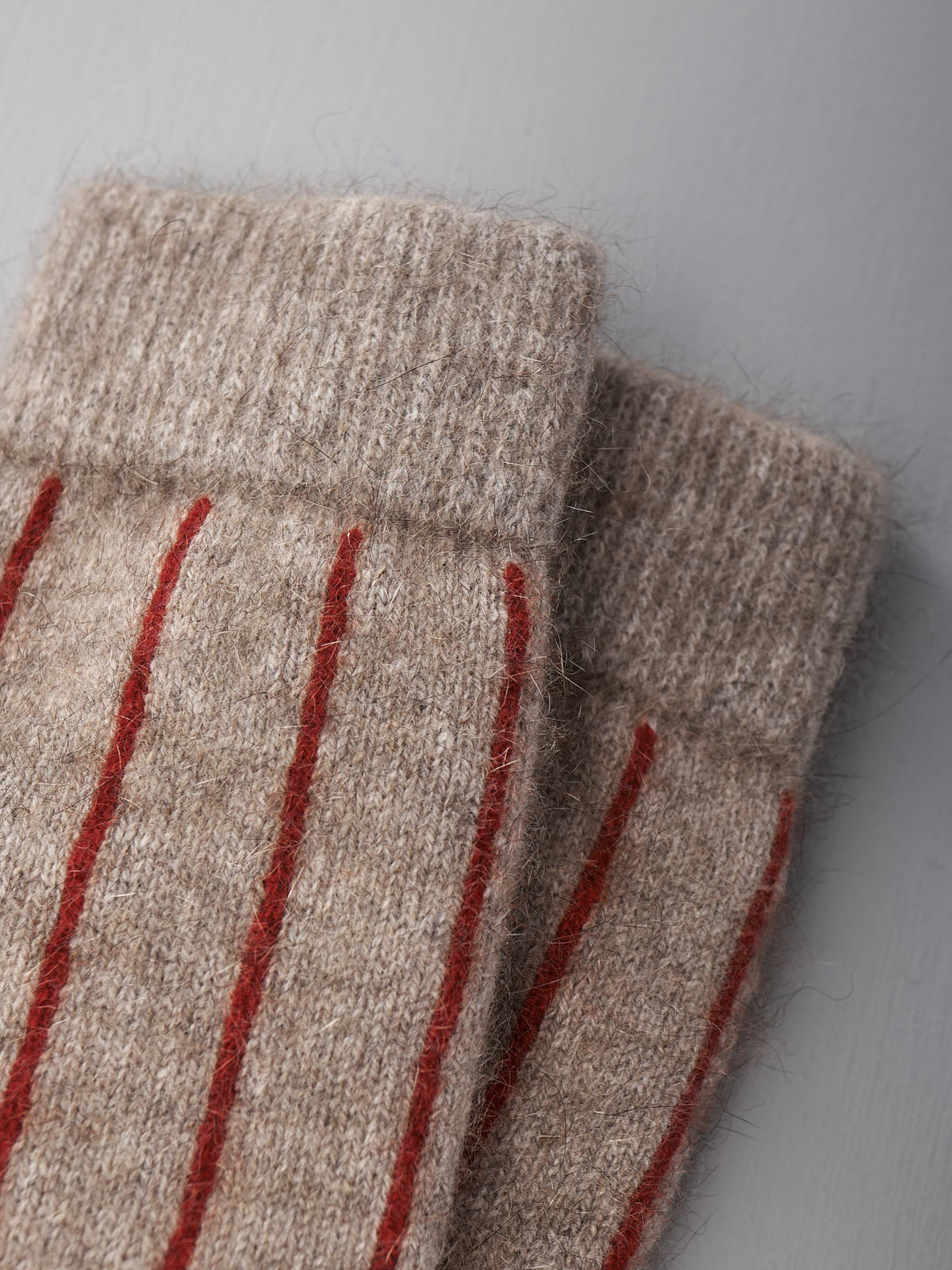 Close-up of Francie’s Possum Merino Socks in Natural &amp; Poppy Stripe, shown on a light gray surface. Available in small, medium, and large—see our size chart for EU, UK, and US sizing to find your best fit.