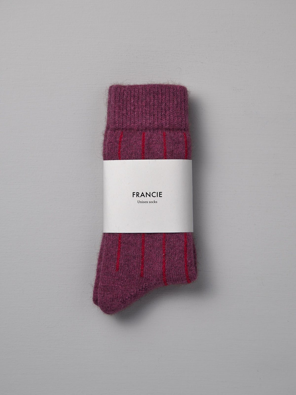 A pair of Francie Possum Merino Socks in Orchid &amp; Poppy Stripe, wrapped in a white label. Available in small, medium, and large sizes for the perfect fit. Displayed on a light gray background.