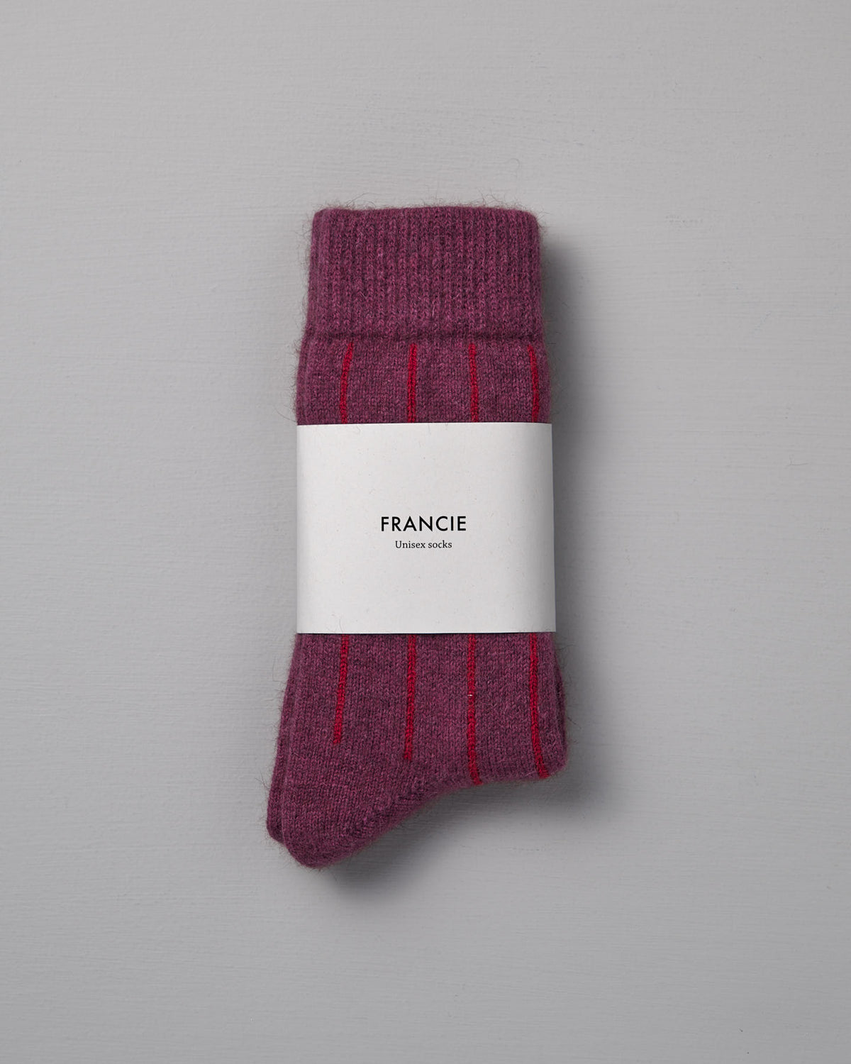 A pair of Francie Possum Merino Socks in Orchid & Poppy Stripe, wrapped in a white label. Available in small, medium, and large sizes for the perfect fit. Displayed on a light gray background.