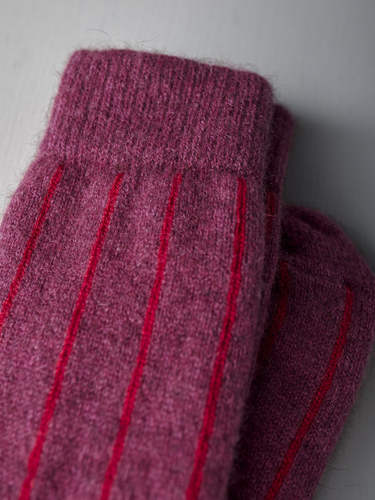 Close-up of Francie Possum Merino Socks in Orchid &amp; Poppy Stripe, shown folded on a light grey surface. Available in small, medium, and large—see our size chart for EU, UK, and US conversions to find your perfect fit.