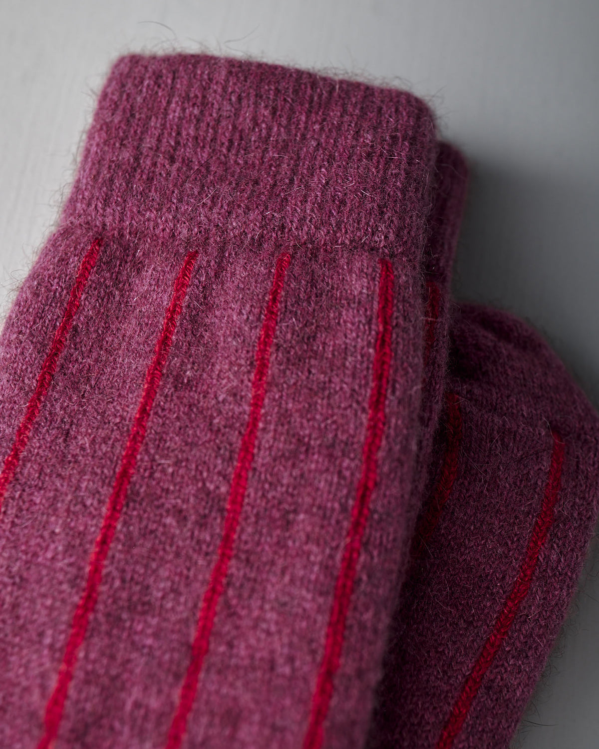 Close-up of Francie Possum Merino Socks in Orchid & Poppy Stripe, shown folded on a light grey surface. Available in small, medium, and large—see our size chart for EU, UK, and US conversions to find your perfect fit.