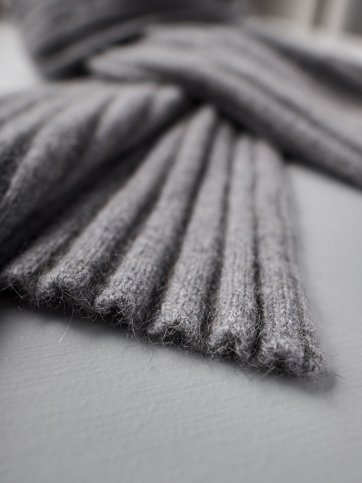 Close-up of the Ripple Scarf in Herb Green by Francie, featuring ribbed knit fabric. The scarf measures 170cm in length and 24cm at its widest point, shown laid flat on a light gray surface.