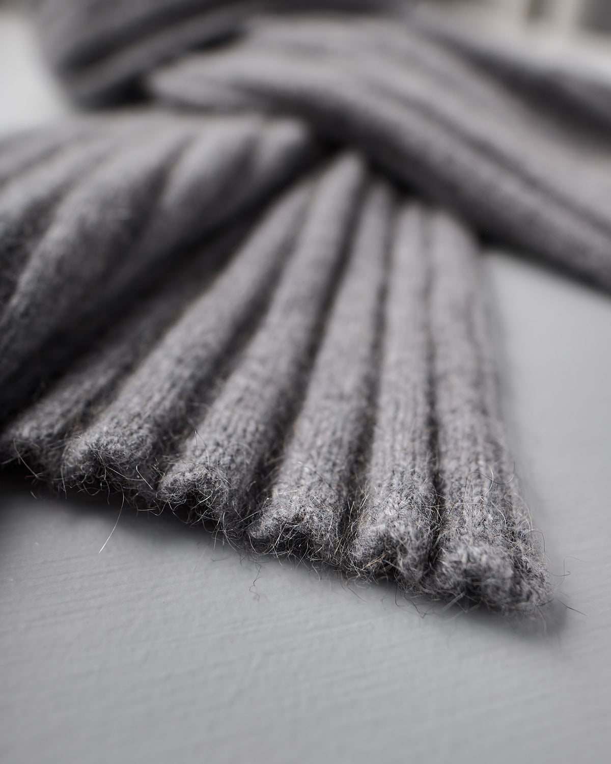 Close-up of the Ripple Scarf in Herb Green by Francie, featuring ribbed knit fabric. The scarf measures 170cm in length and 24cm at its widest point, shown laid flat on a light gray surface.
