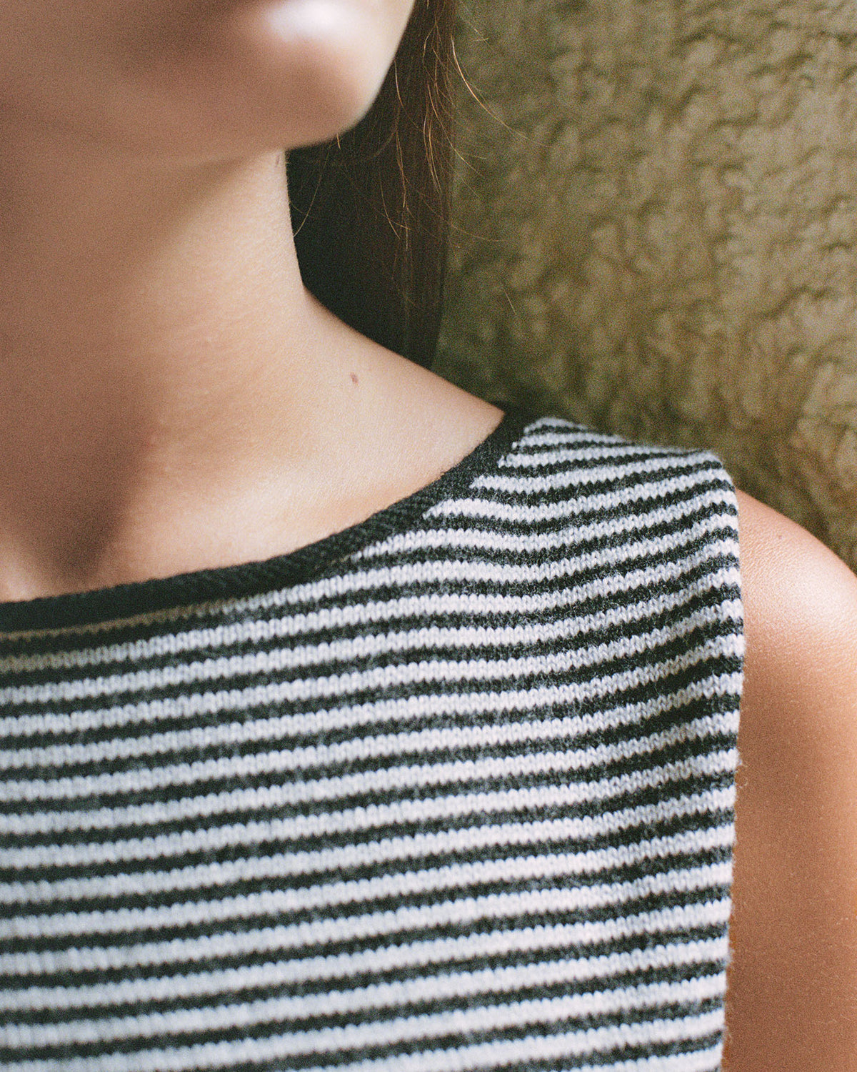 Close-up of a person wearing Francie's Striped Star Vest in Black & Creme, a sleeveless, relaxed-fit top, against a textured background.