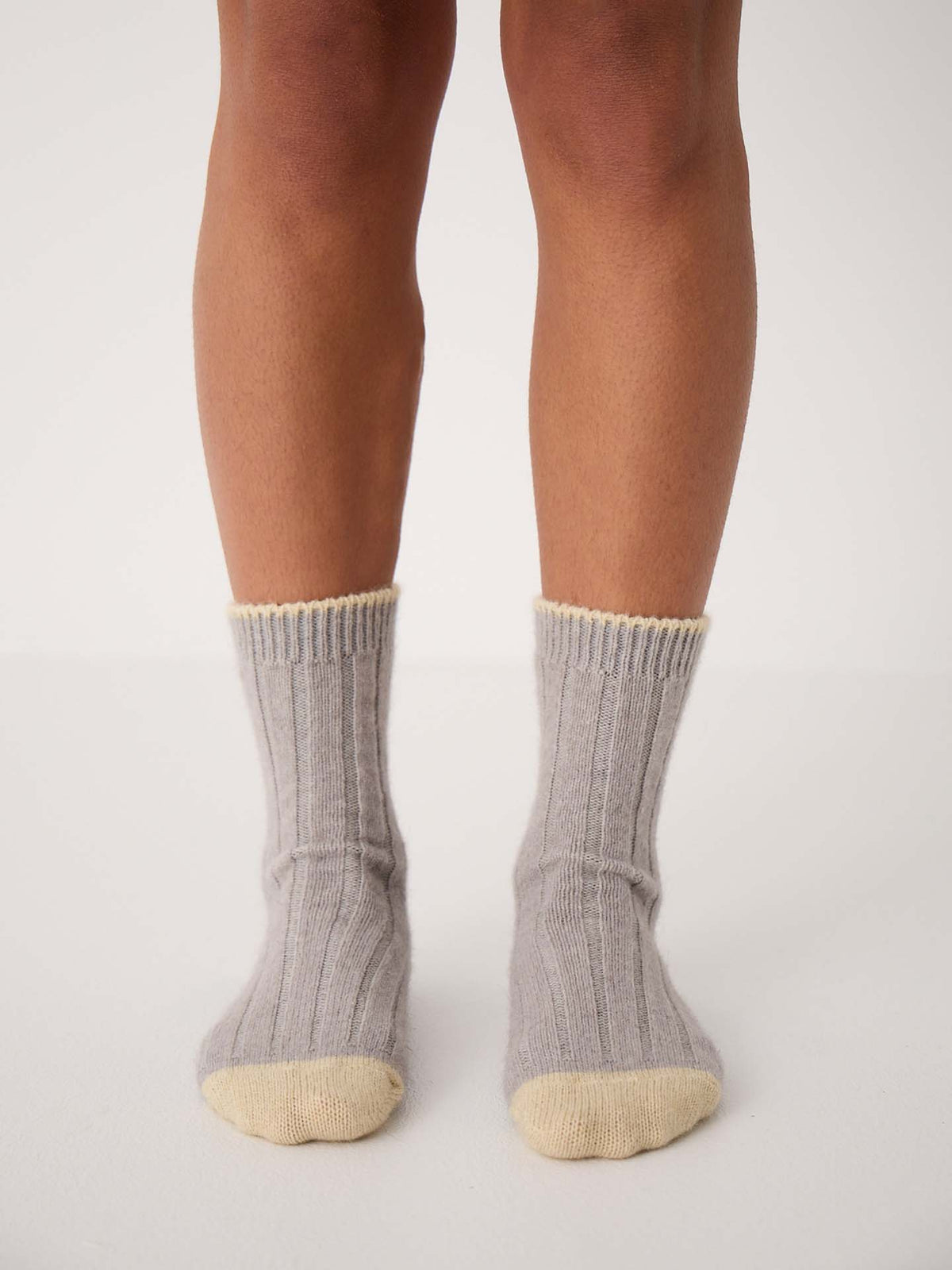 Someone stands on a white surface wearing Yin & Yang Socks – Pearl & Creme Toe, gray ribbed socks with cream-colored toes and cuffs—ideal for referencing shoe size charts or checking EU, UK, and US sizing conversions.