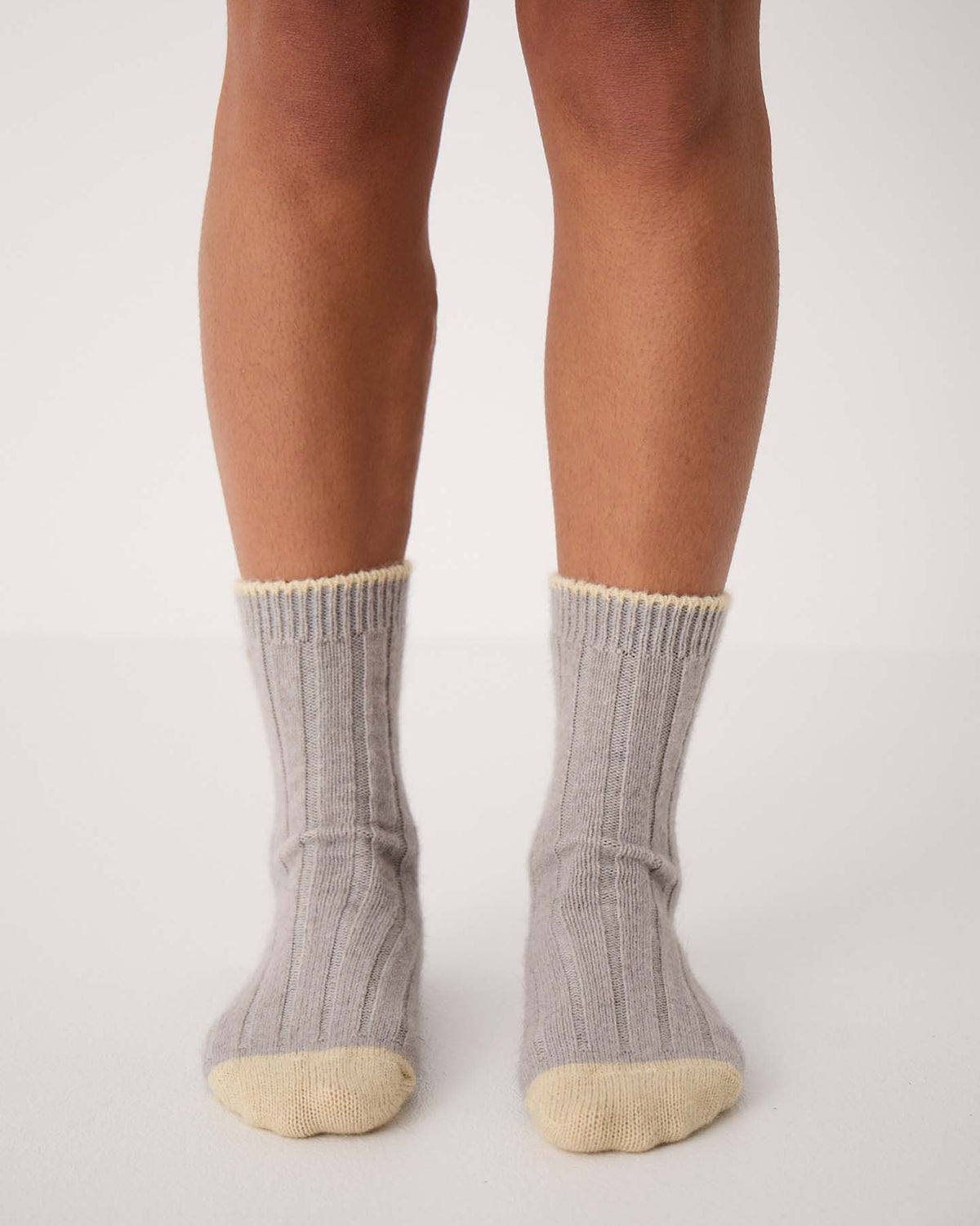 Someone stands on a white surface wearing Yin & Yang Socks – Pearl & Creme Toe, gray ribbed socks with cream-colored toes and cuffs—ideal for referencing shoe size charts or checking EU, UK, and US sizing conversions.