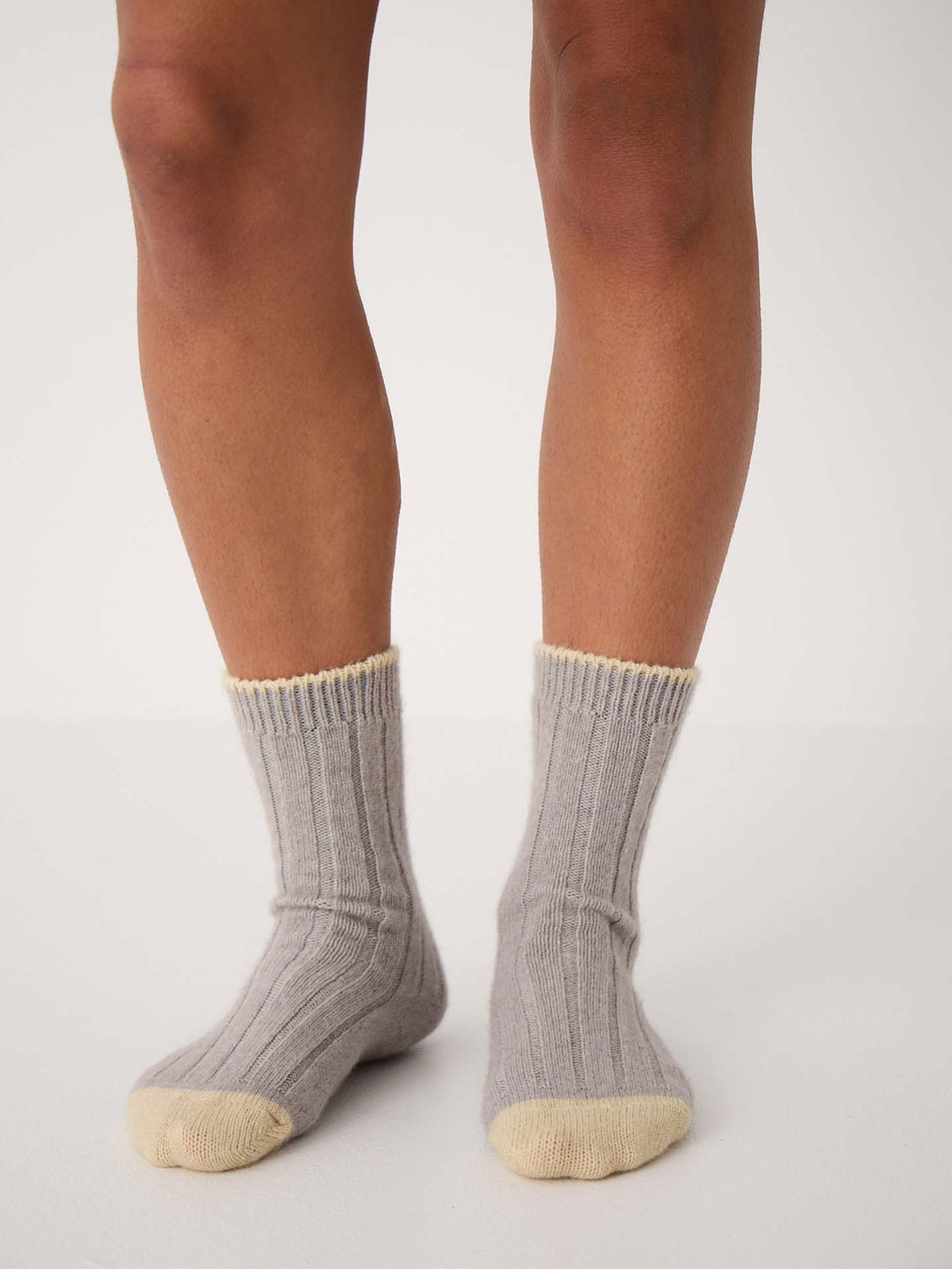 Wearing Yin & Yang Socks – Pearl & Creme Toe, someone stands on a light floor, possibly checking a shoe size chart for the perfect fit.