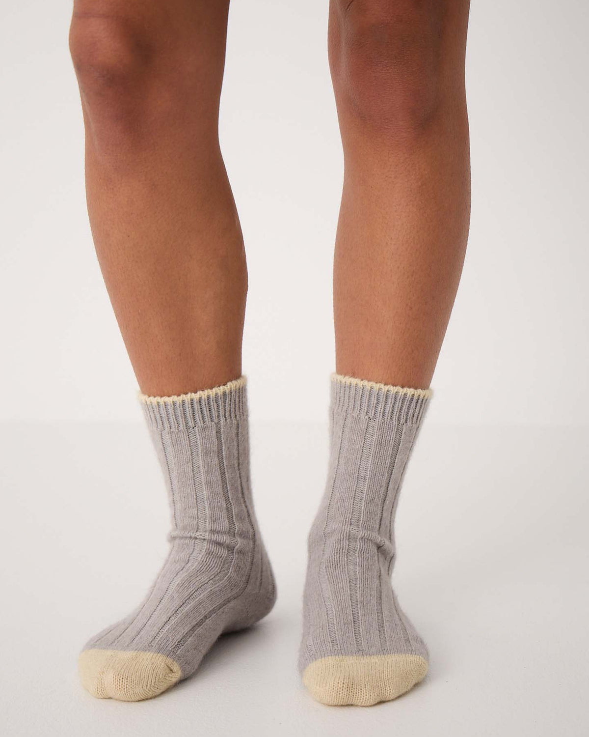 Wearing Yin & Yang Socks – Pearl & Creme Toe, someone stands on a light floor, possibly checking a shoe size chart for the perfect fit.