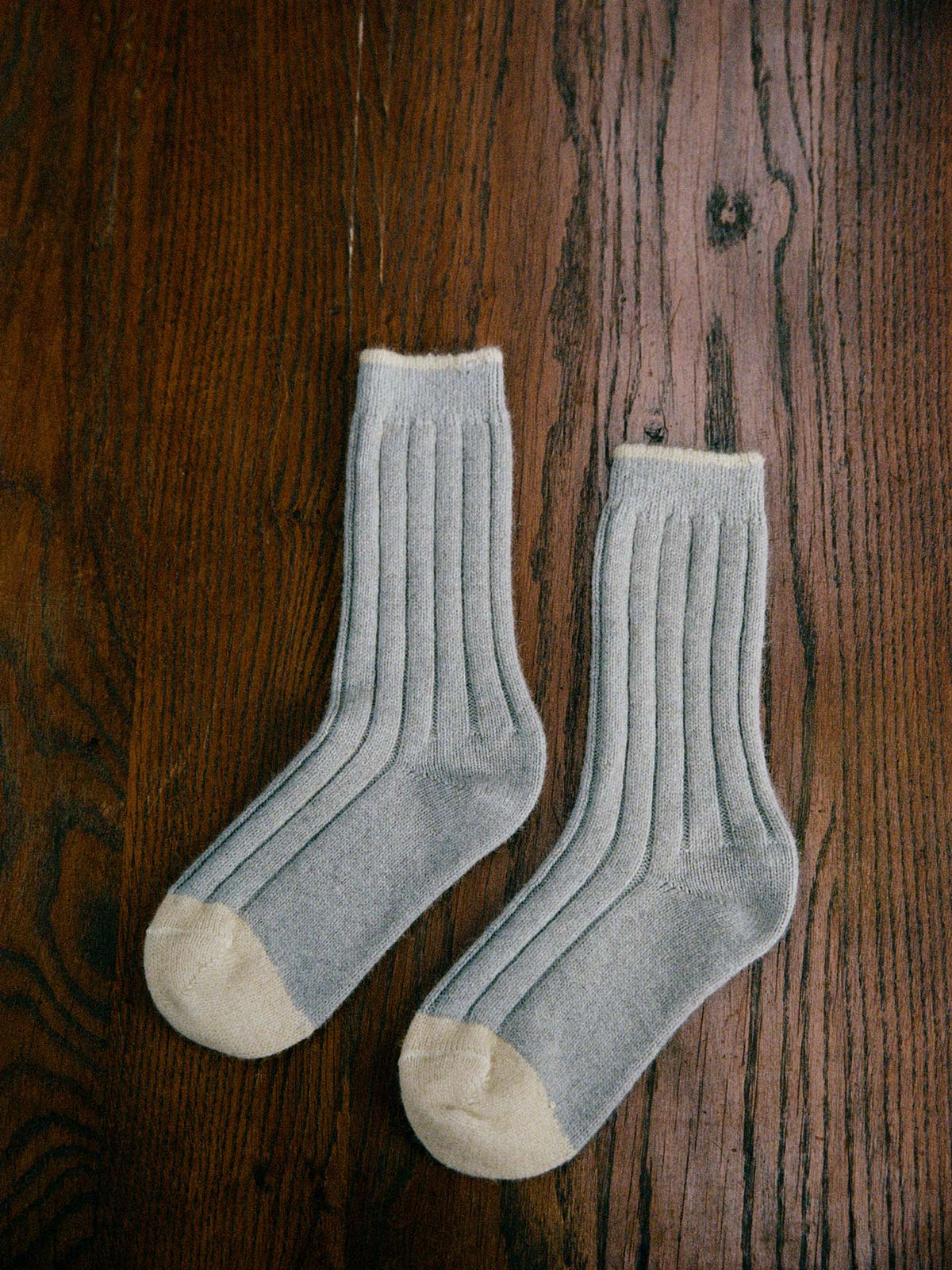 The Yin & Yang Socks – Pearl & Creme Toe feature a gray ribbed design with beige toes and cuffs, displayed on a wooden floor—perfect for easy EU, UK, and US size conversion seekers.
