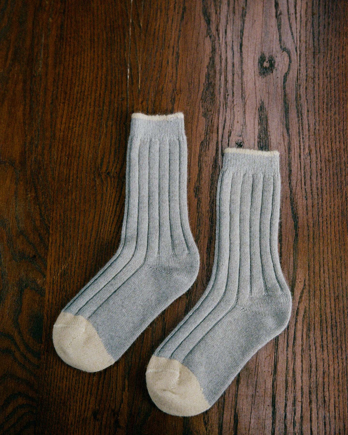 The Yin & Yang Socks – Pearl & Creme Toe feature a gray ribbed design with beige toes and cuffs, displayed on a wooden floor—perfect for easy EU, UK, and US size conversion seekers.