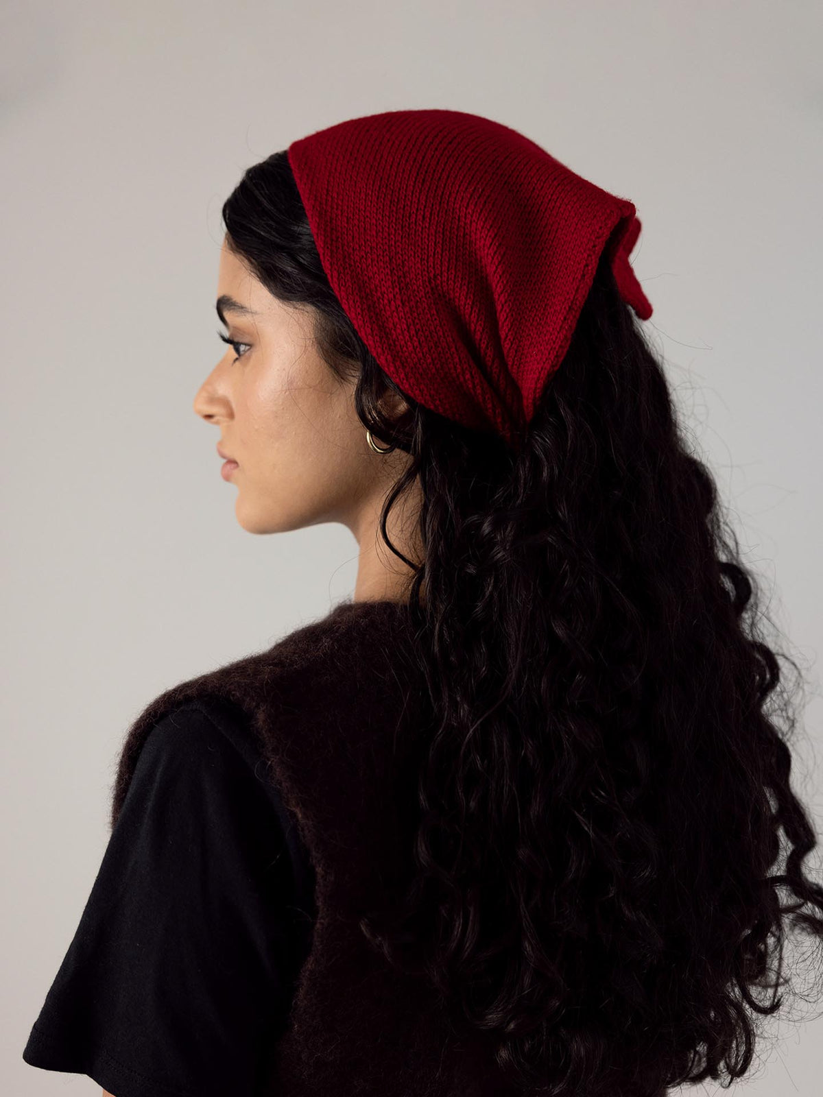 The back view of a woman wearing a Daisy Scarf – Crimson headband, crafted from ethically made Merino Wool by Francie.