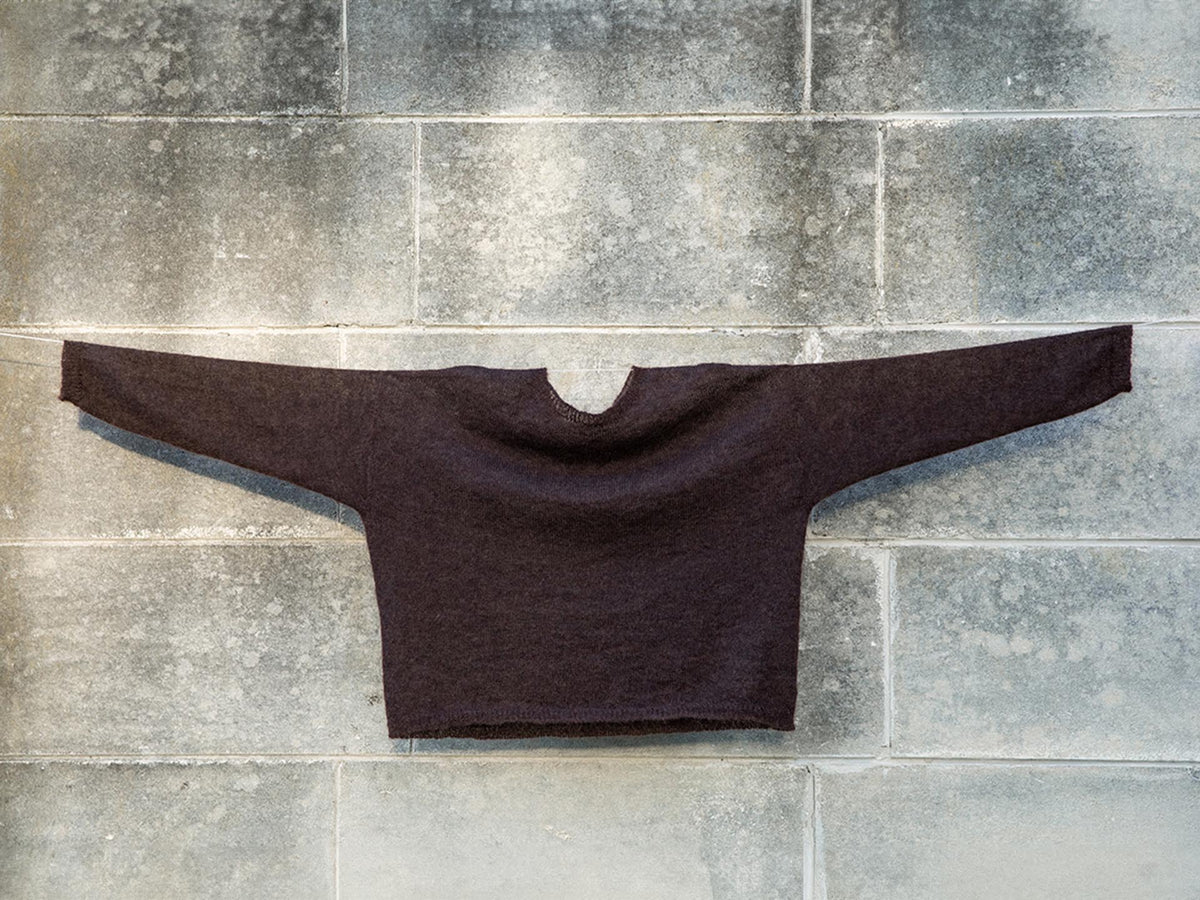 A Feather Knit – Cocoa sweater hanging on a wall by Francie.