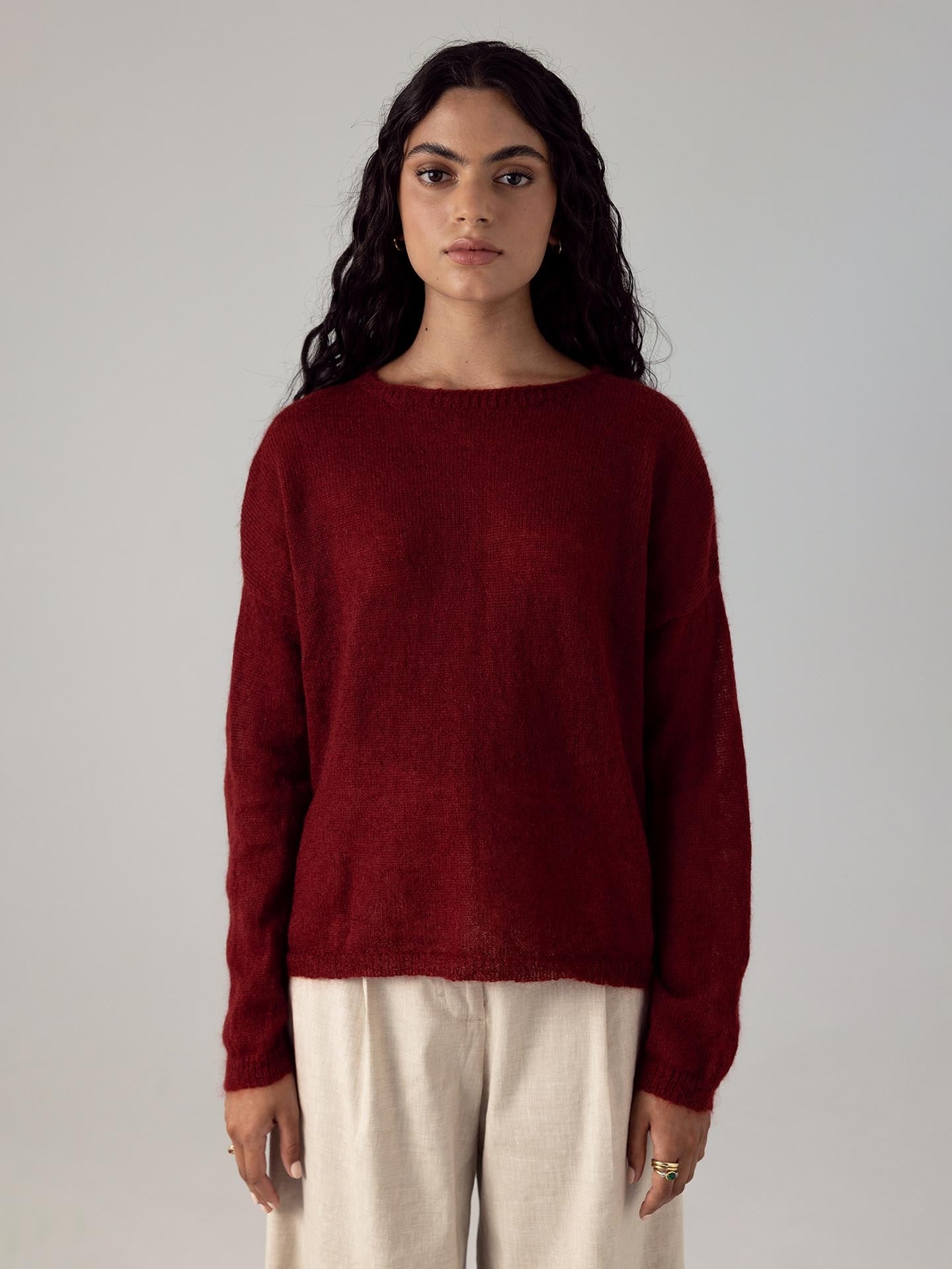 The model is wearing a Francie Feather Knit – Dark Cherry sweater and beige pants.