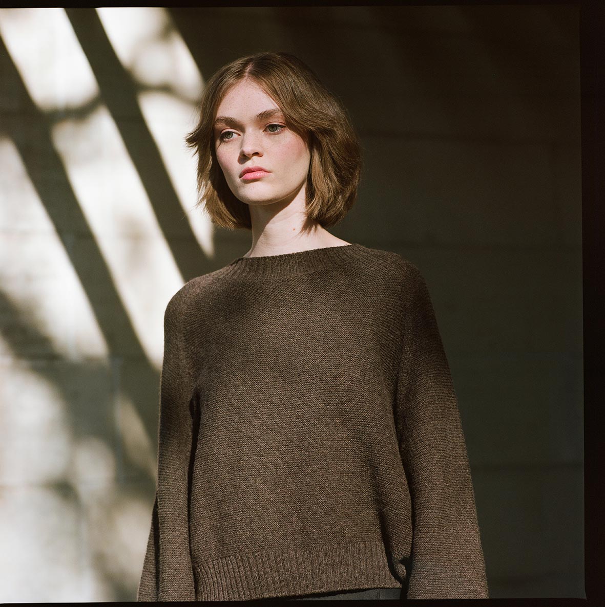 A woman wearing a Francie Poet Knit - Truffle sweater and black pants.