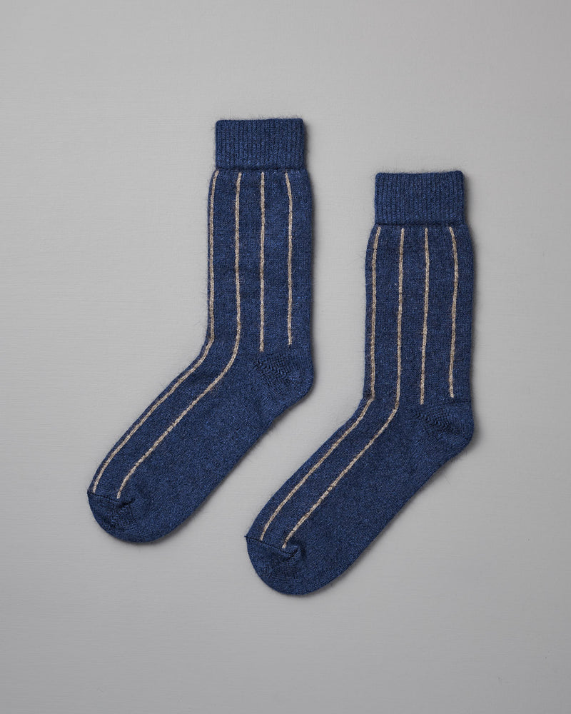 A pair of Francie Possum Merino Socks – Blue & Natural Stripe lying flat on a light gray surface.