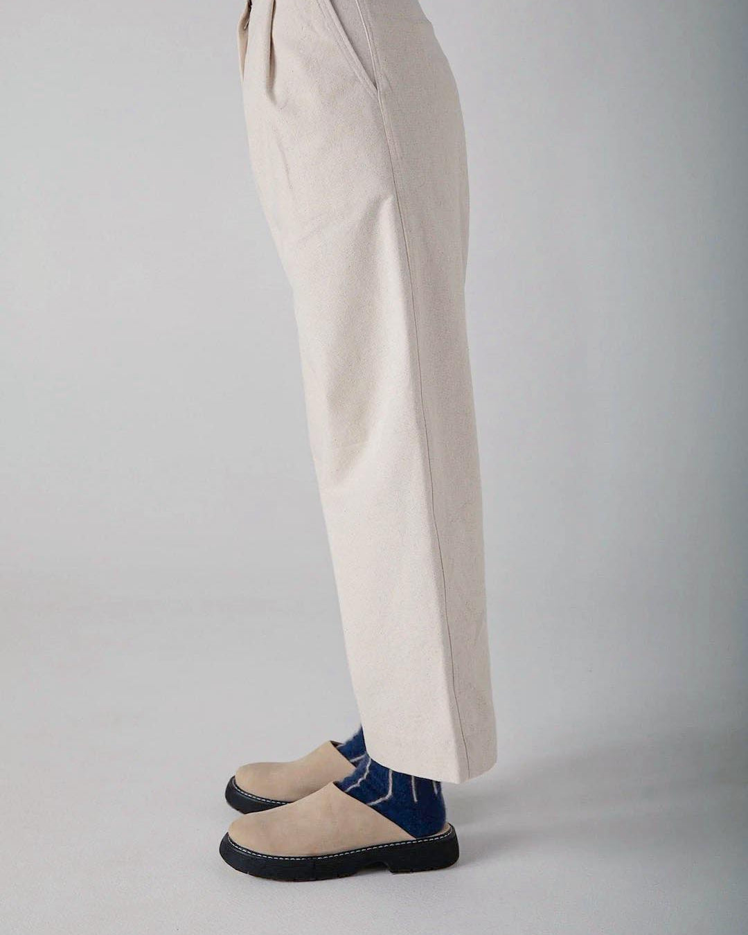 A person standing in a neutral pose showcasing soft, light-colored trousers and Francie dark blue espadrilles against a plain background.