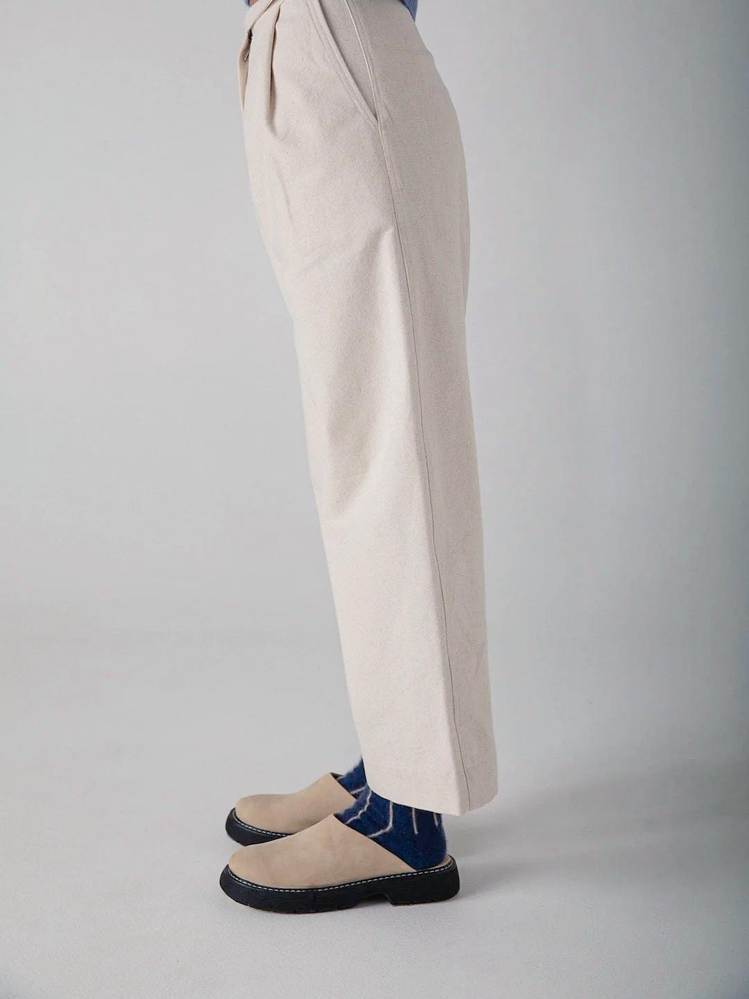 A person standing in a neutral pose showcasing soft, light-colored trousers and Francie dark blue espadrilles against a plain background.