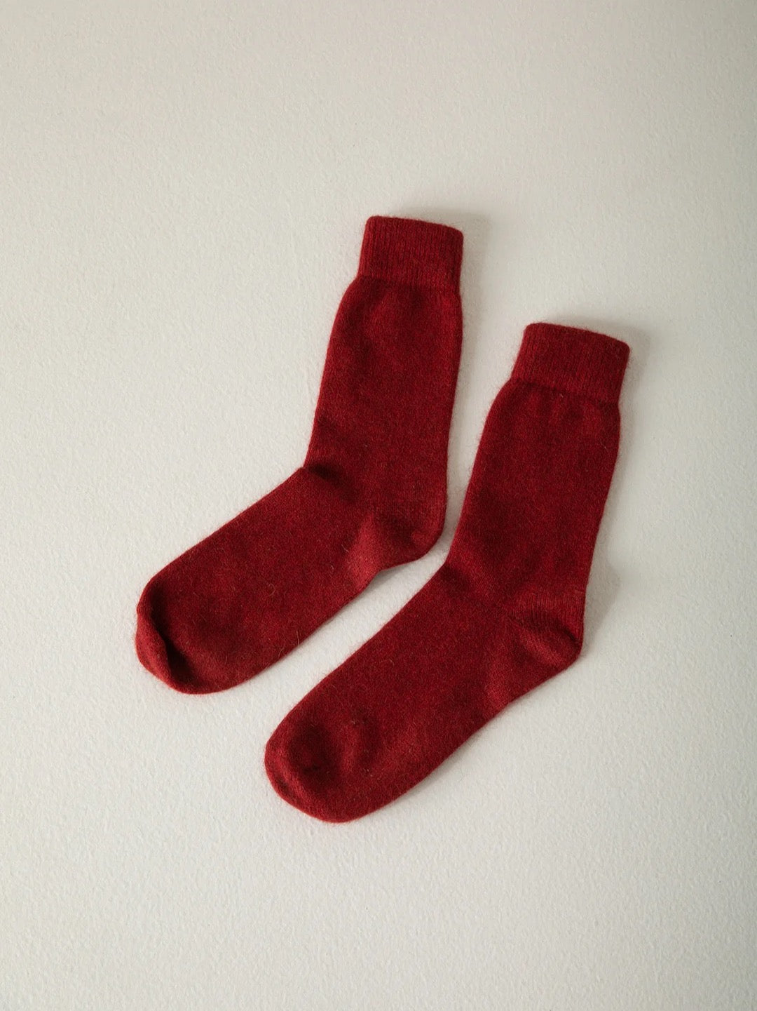 A pair of Francie Possum Merino Socks – Crimson, suitable for various shoe sizes, laid flat on a light beige background.