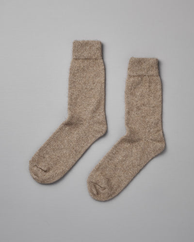 A pair of Possum Merino Socks – Natural from Francie laid flat on a gray surface.