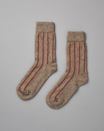 A pair of beige Possum Merino Socks by Francie with red stripes on a light gray background.