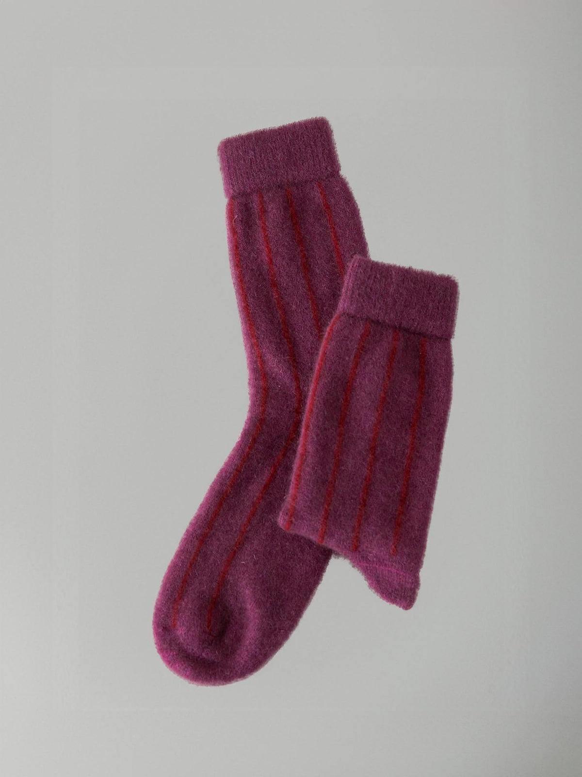 A pair of Possum Merino Socks - Orchid &amp; Poppy Stripe by Francie against a neutral background.