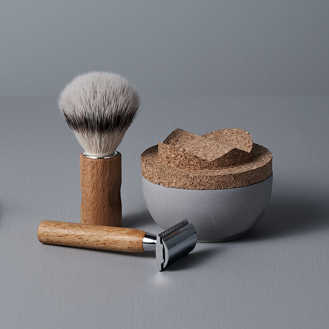 Shaving set includes a wooden-handled shaving brush, a safety razor, and a ceramic shaving bowl with a cork lid, placed on a gray surface.